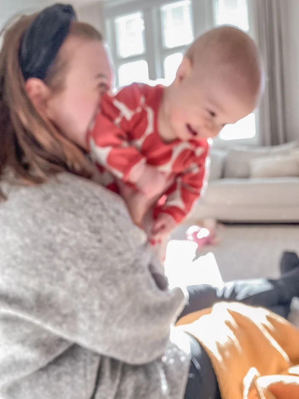 Nainen pitää sylissä pientä lasta, joka nauraa ja katsoo poispäin.