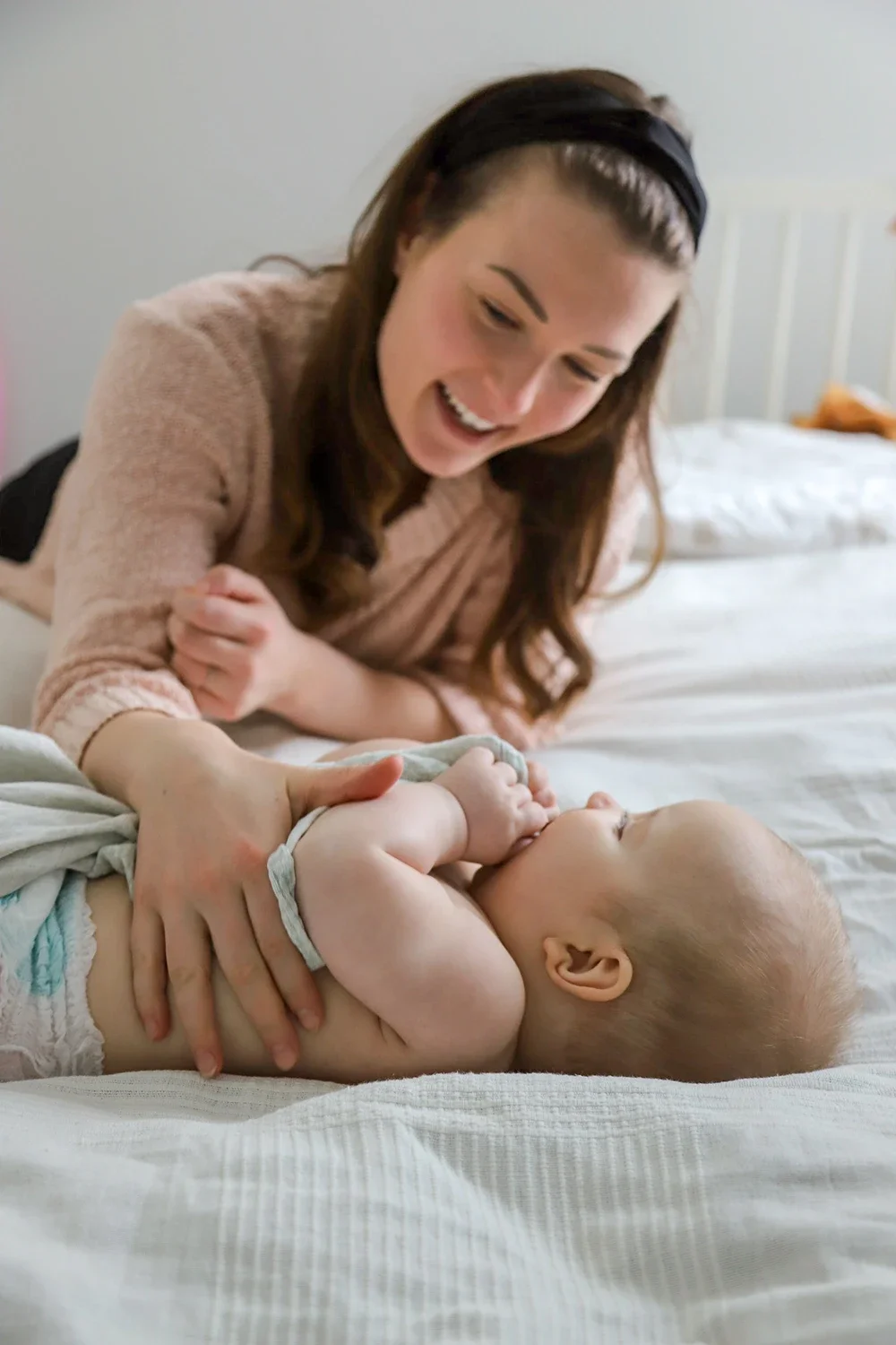 Nainen leikkii vauvan kanssa makuuhuoneessa.