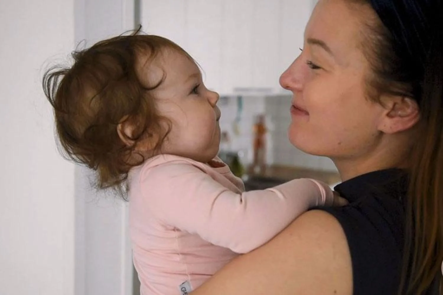 Lastenhoitaja pitää pientä lasta sylissä ja hymyilee