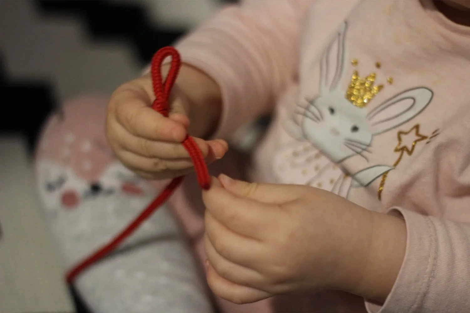 Lapsi kiinnittää punaista narua sormillaan.