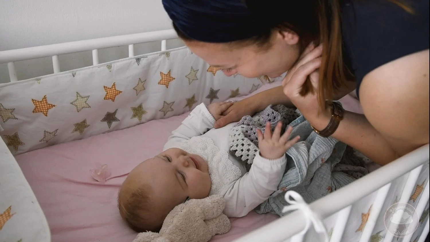 Lastenneuvolassa hoitaja ja vauva hymyilevät toisiaan katsellen.