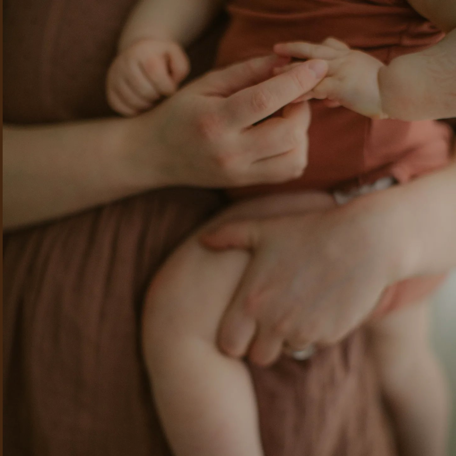 Vauva on aikuisen sylissä pitäen kädestä kiinni.