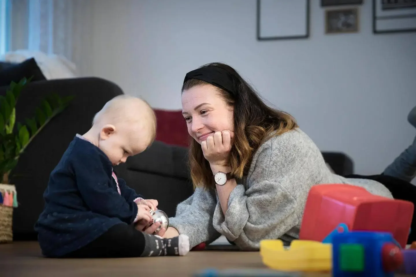 Nainen ja lapsi leikkivät lattialla leluilla.