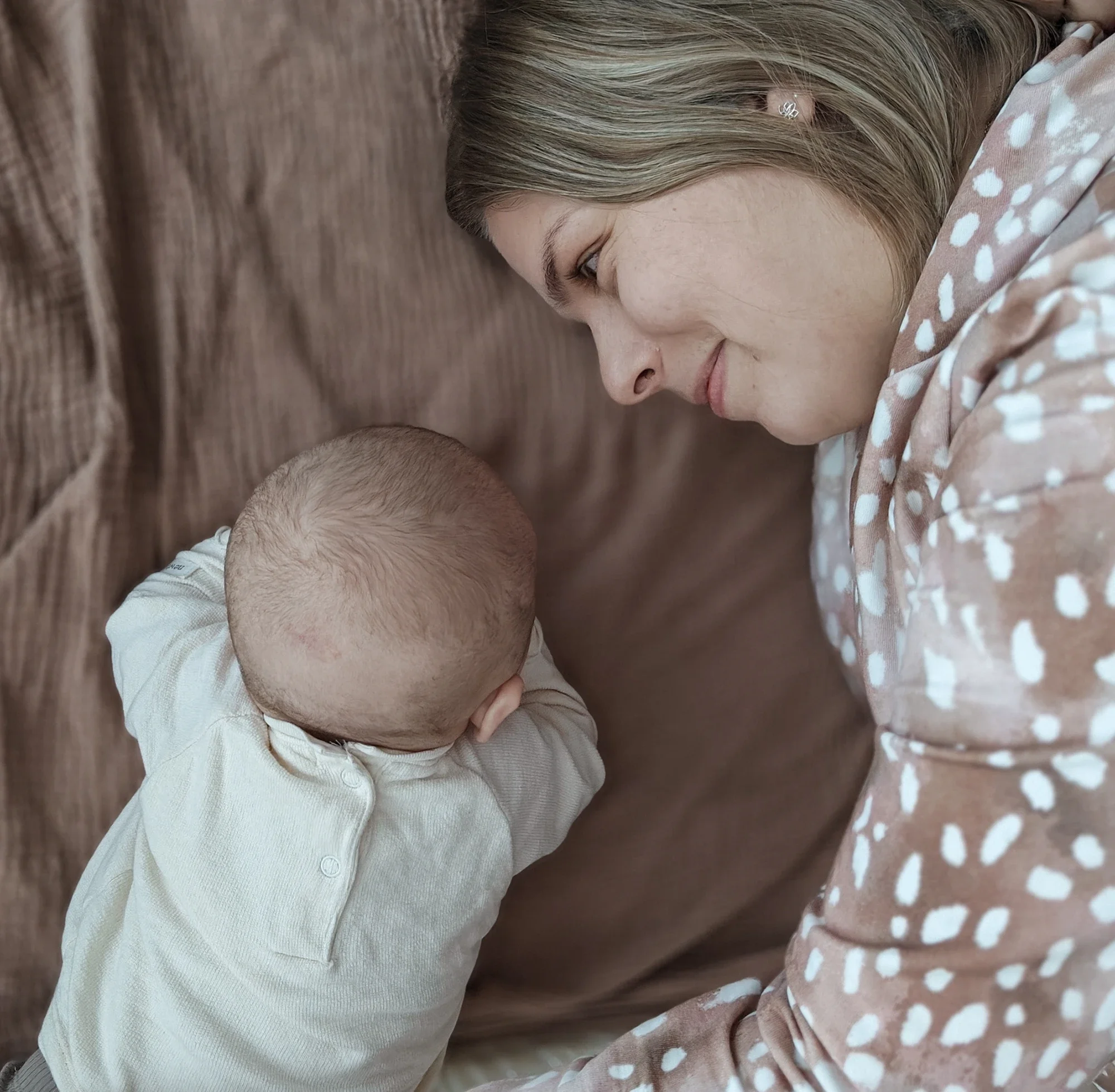 Nuori nainen katsoo lasta, joka makaa vatsallaan ja katsoo kohti häntä, heidän välillään on yhteys.