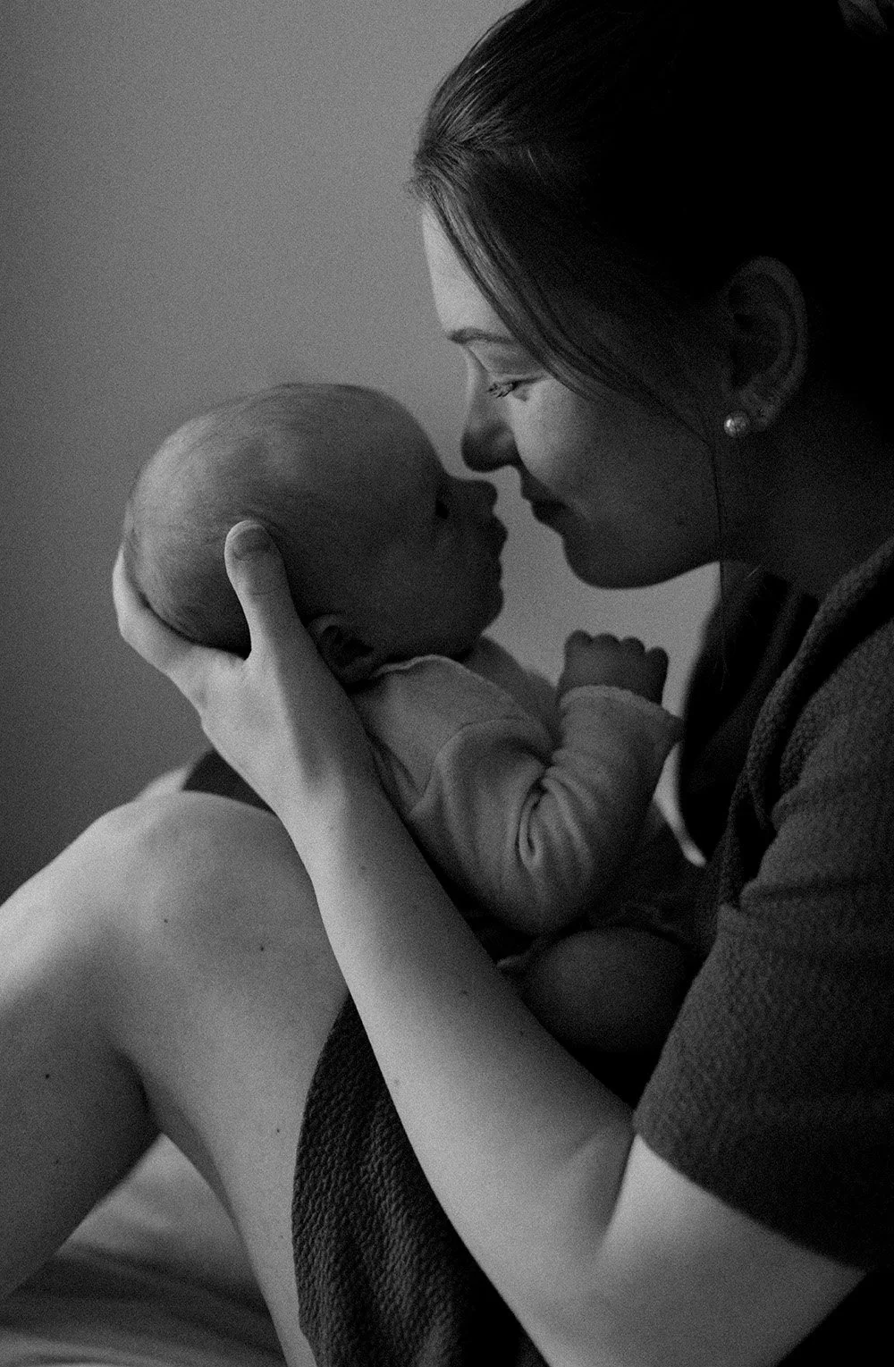 Mustavalkoinen kuva äidistä ja vauvasta, jossa äiti pitää vauvaa kädessään ja katsovat toisiaan läheisesti.