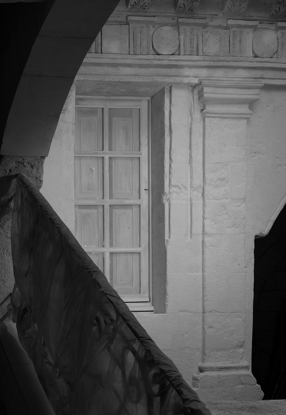 Photo en noir et blanc montrant une fenêtre en bois sur un mur en pierre à l'Hôtel de Viguier, un ancien hotel particulier à Arles récemment rénové.