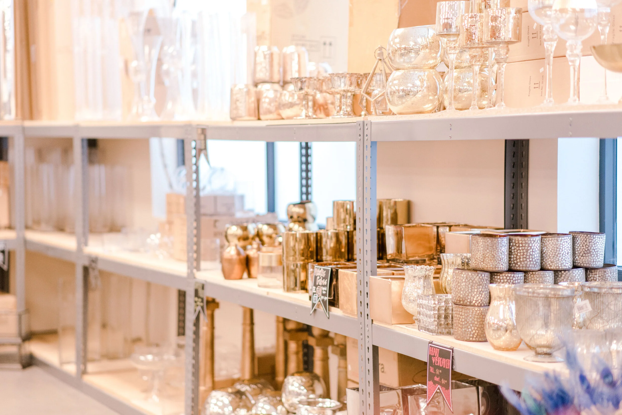Metal shelves filled with various glass vases and candle holders in a store.
