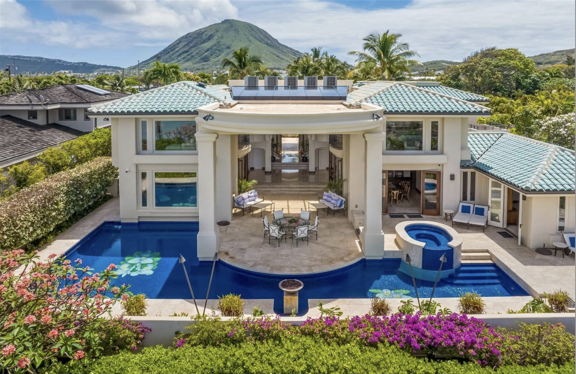 A luxurious white house with a swimming pool, hot tub, and outdoor seating area set against a backdrop of a green mountain and lush tropical trees.and premium architectural detail. Perfect for developers, agents, and designers.