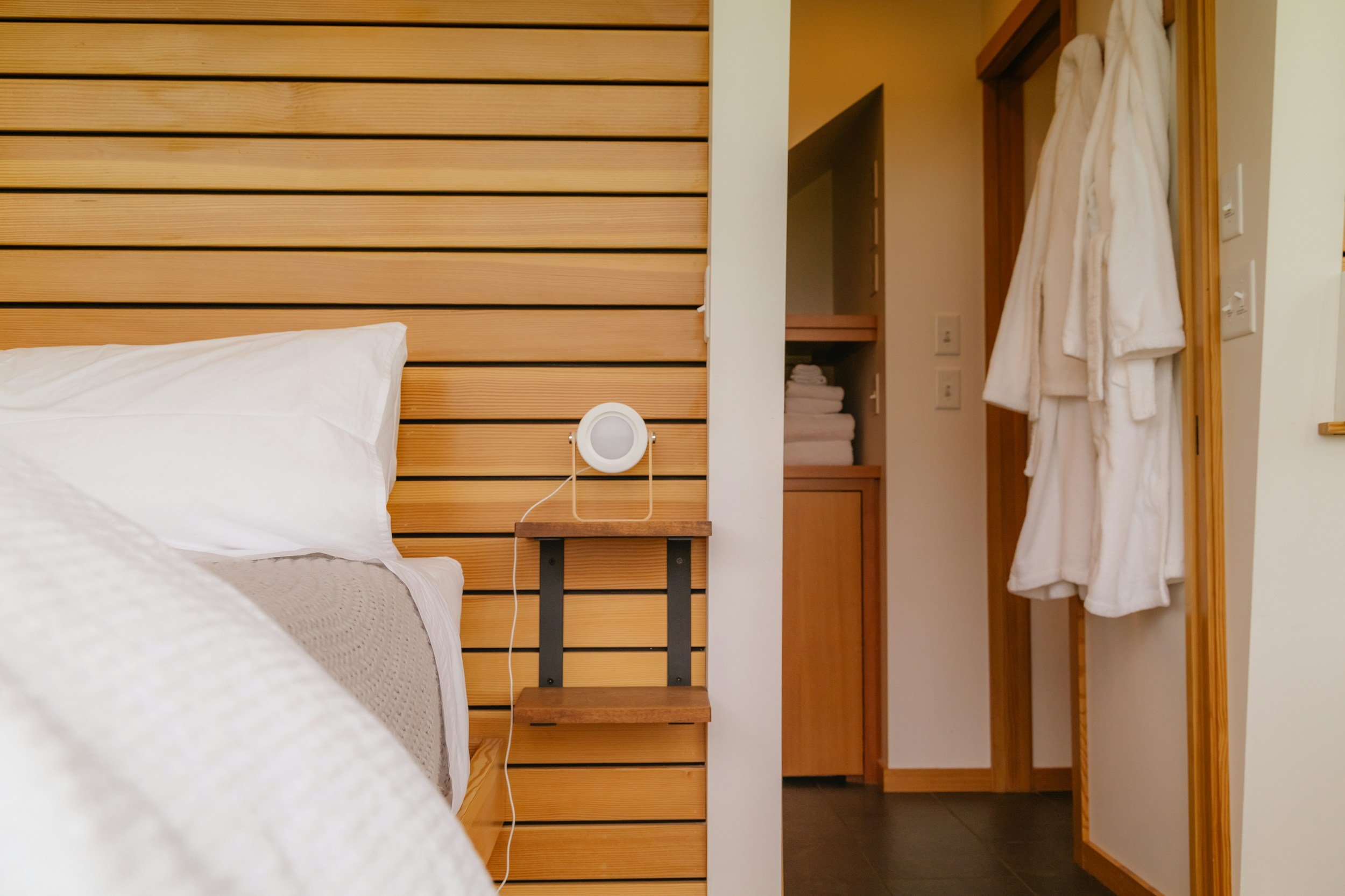 Modern Airbnb bedroom with wooden headboard, cozy bedding and bathrobe in stylish rental apartment