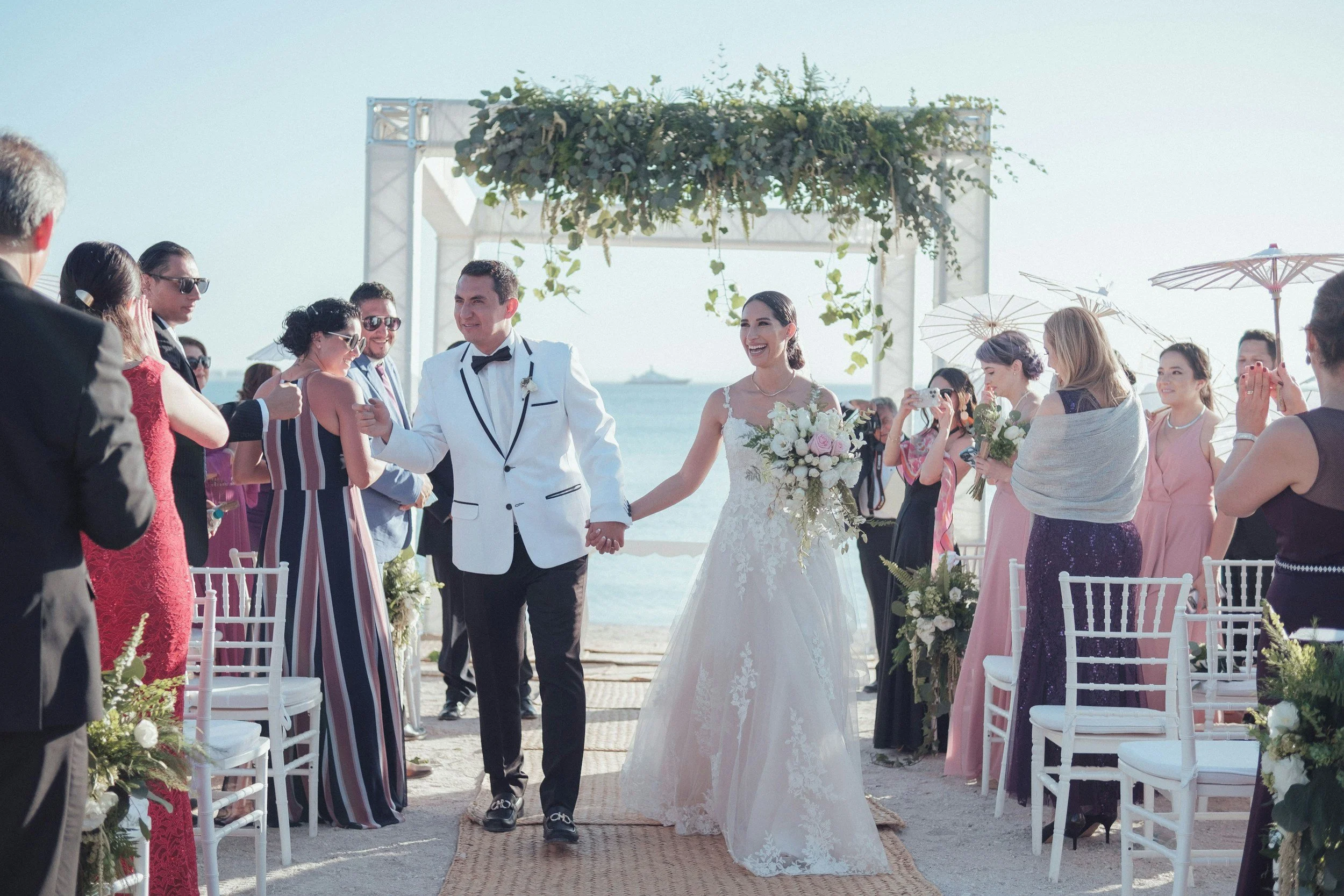 Beach wedding ceremony with bride and groom walking down the aisle