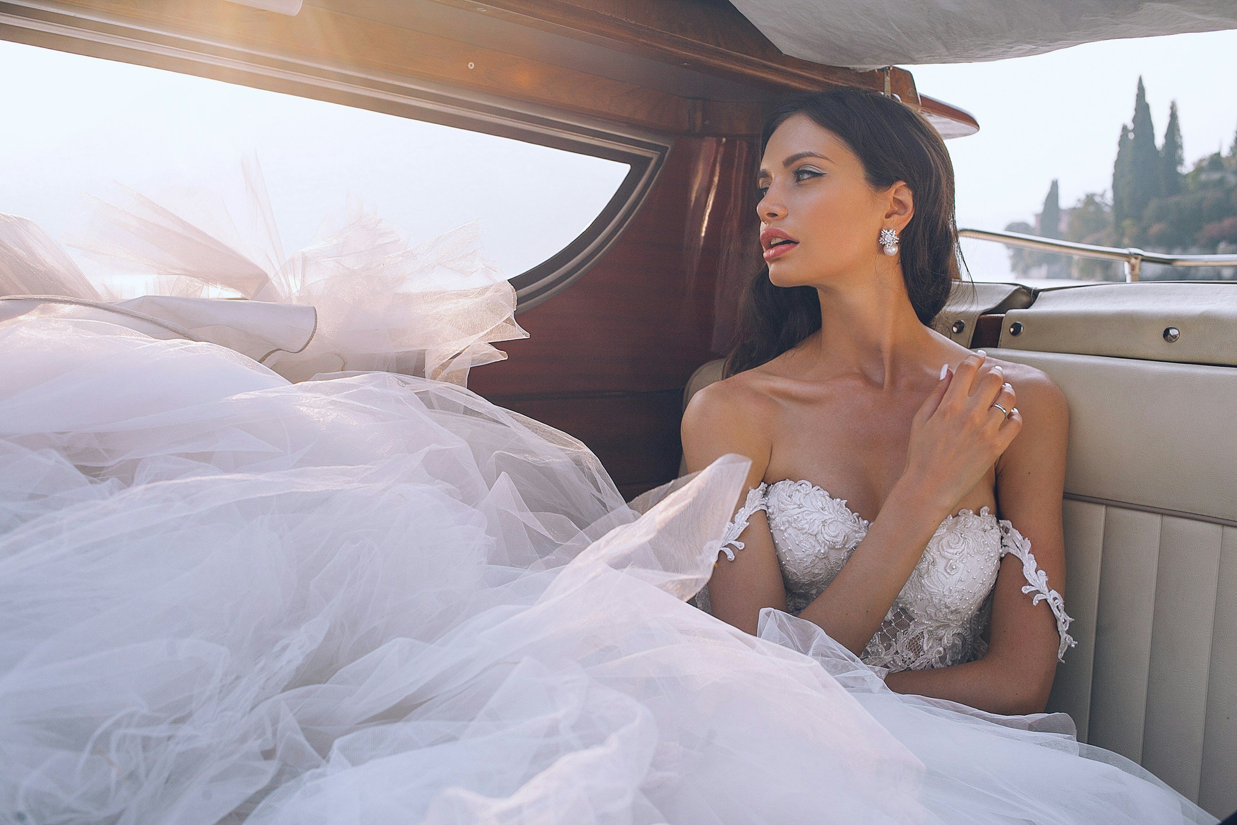 Bride in a luxury wedding dress sitting in a vintage car