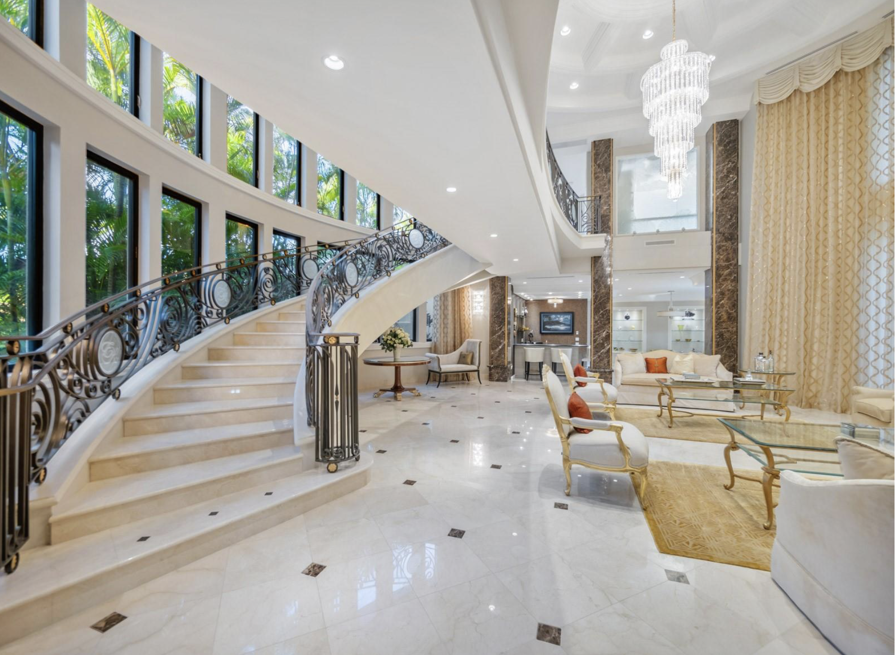 Luxury real estate interior photography showcasing a breathtaking grand staircase, elegant marble flooring, and a spacious double-height living area.