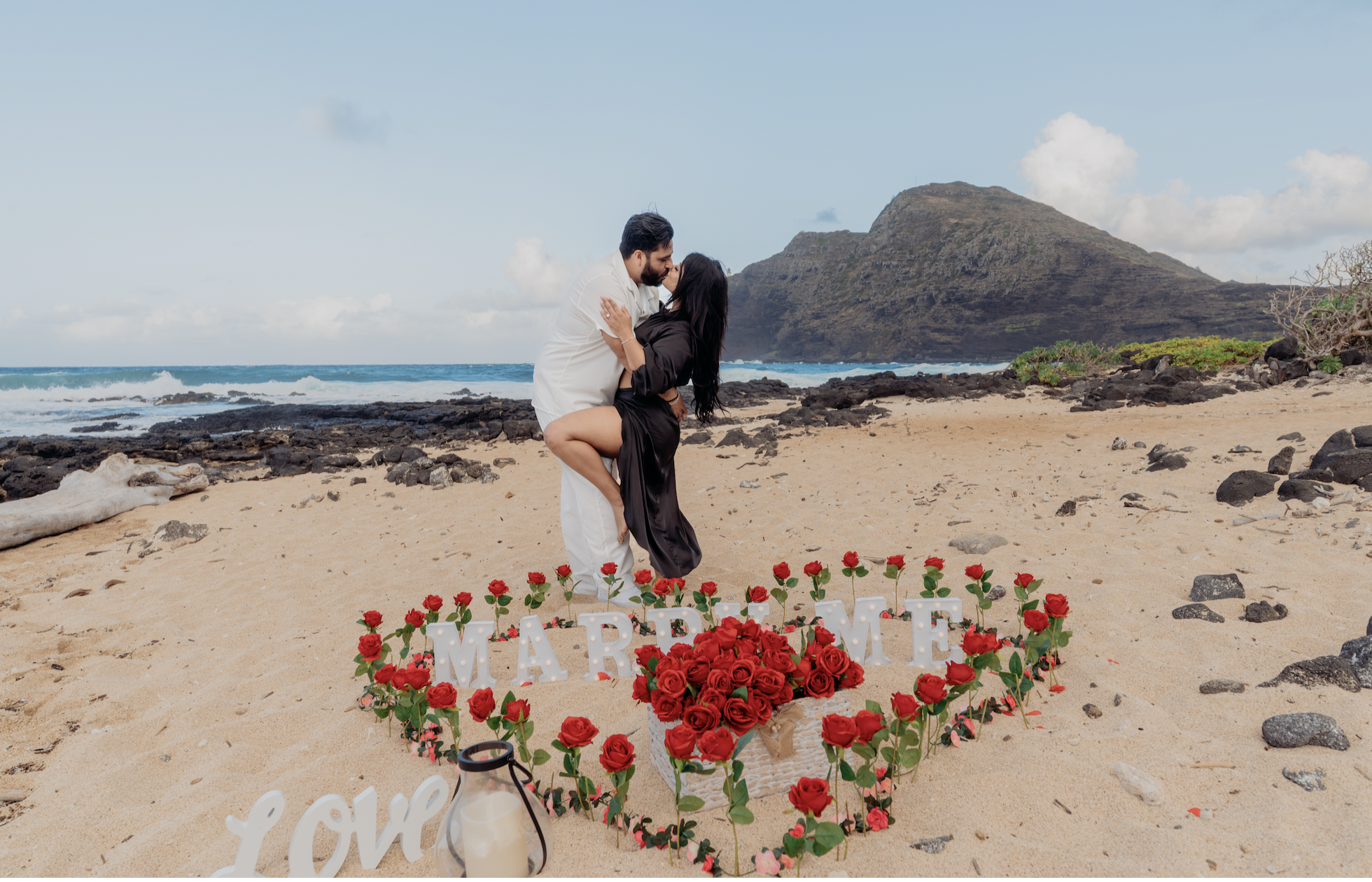 Romantic engagement photoshoot on the beach with rose decorations, creative posing idea for couples