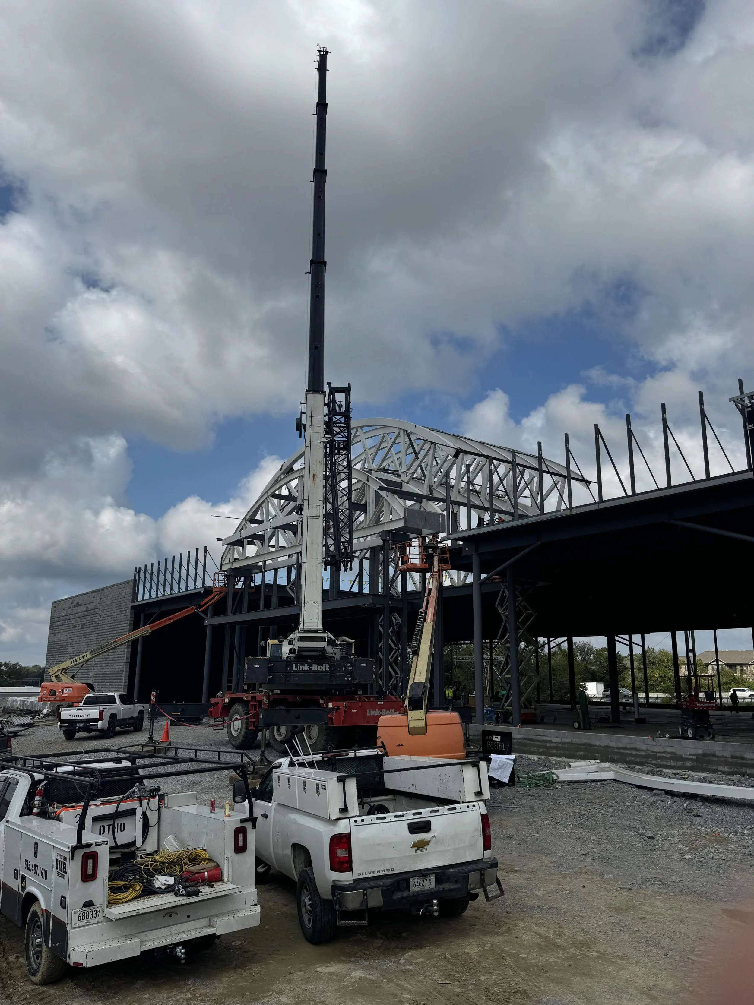 Construction site with crane and building framework, vehicles, and equipment.