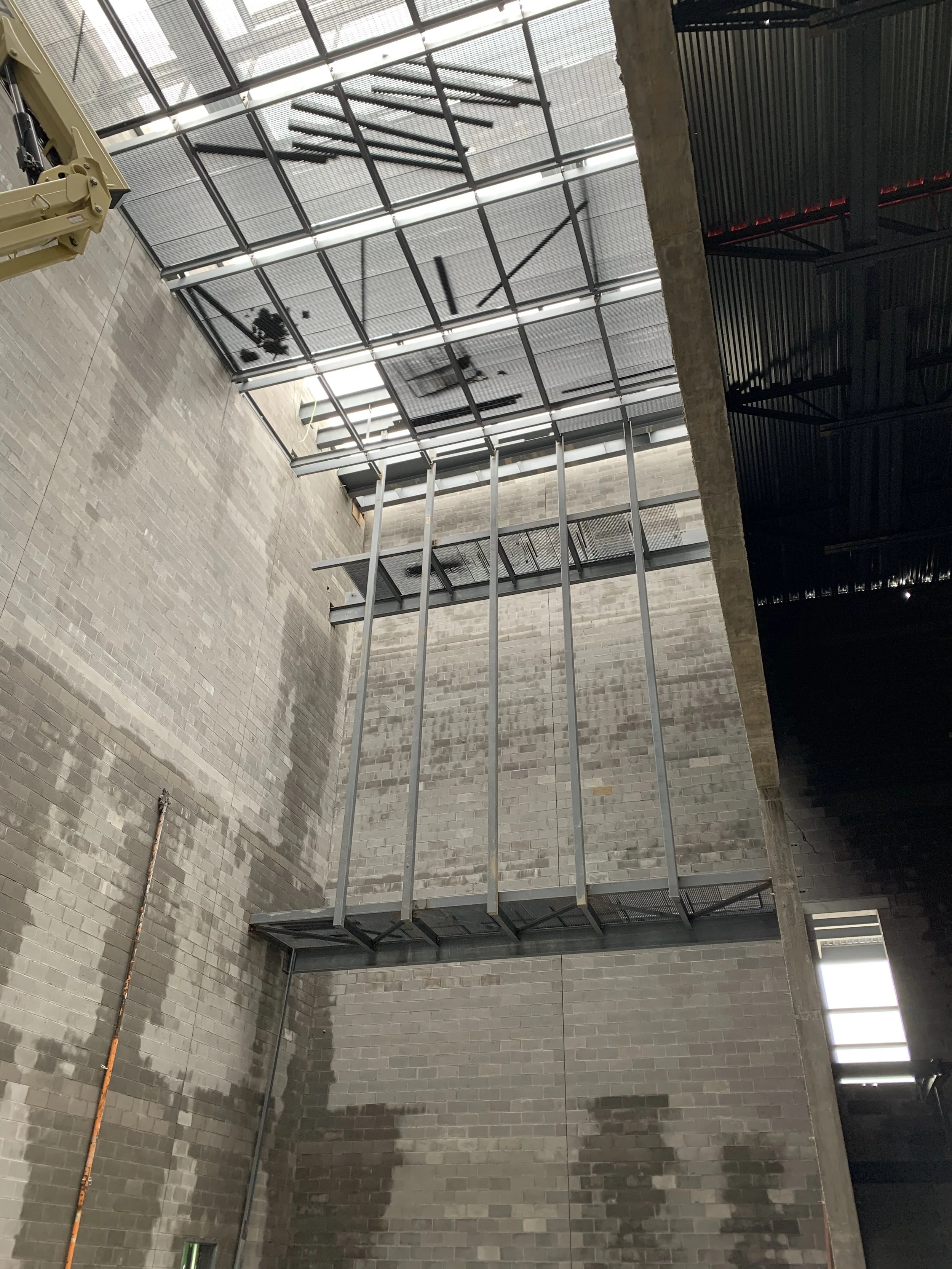 Interior of a building with brick walls, a metal platform, and a large glass ceiling.