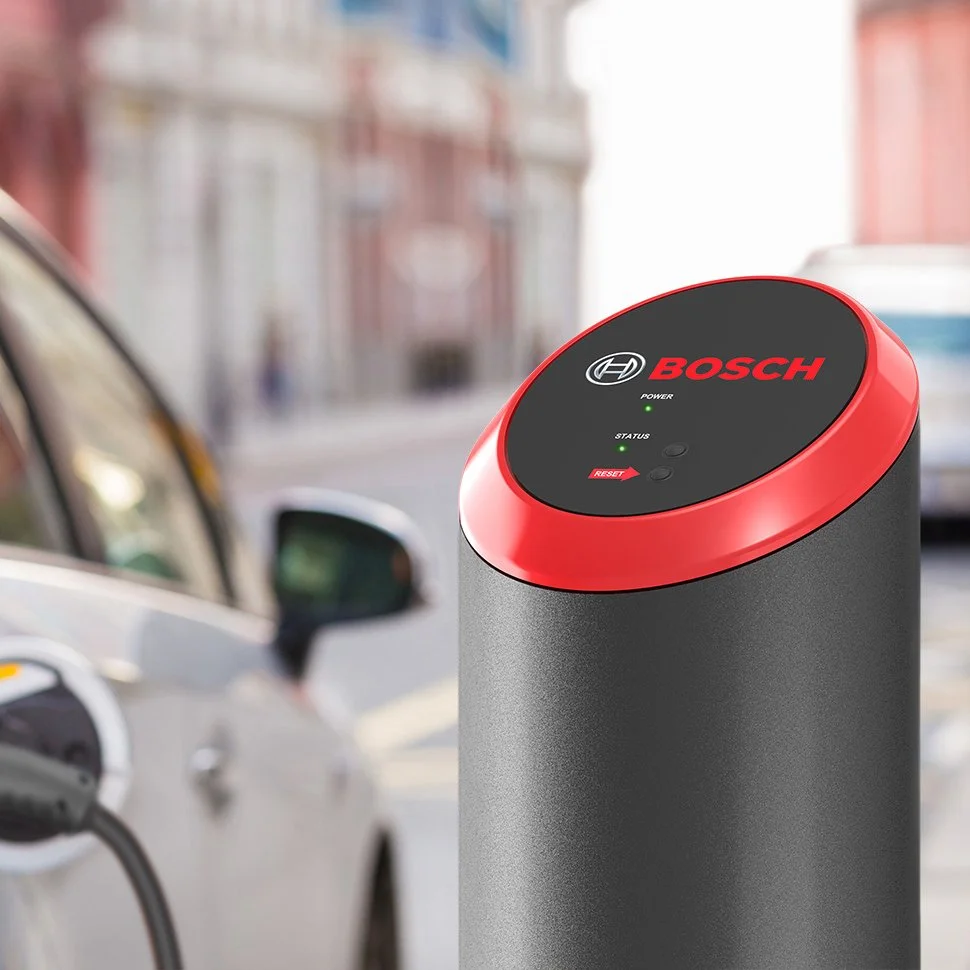 Bollard-style Bosch EV charger with a car and city street in the background