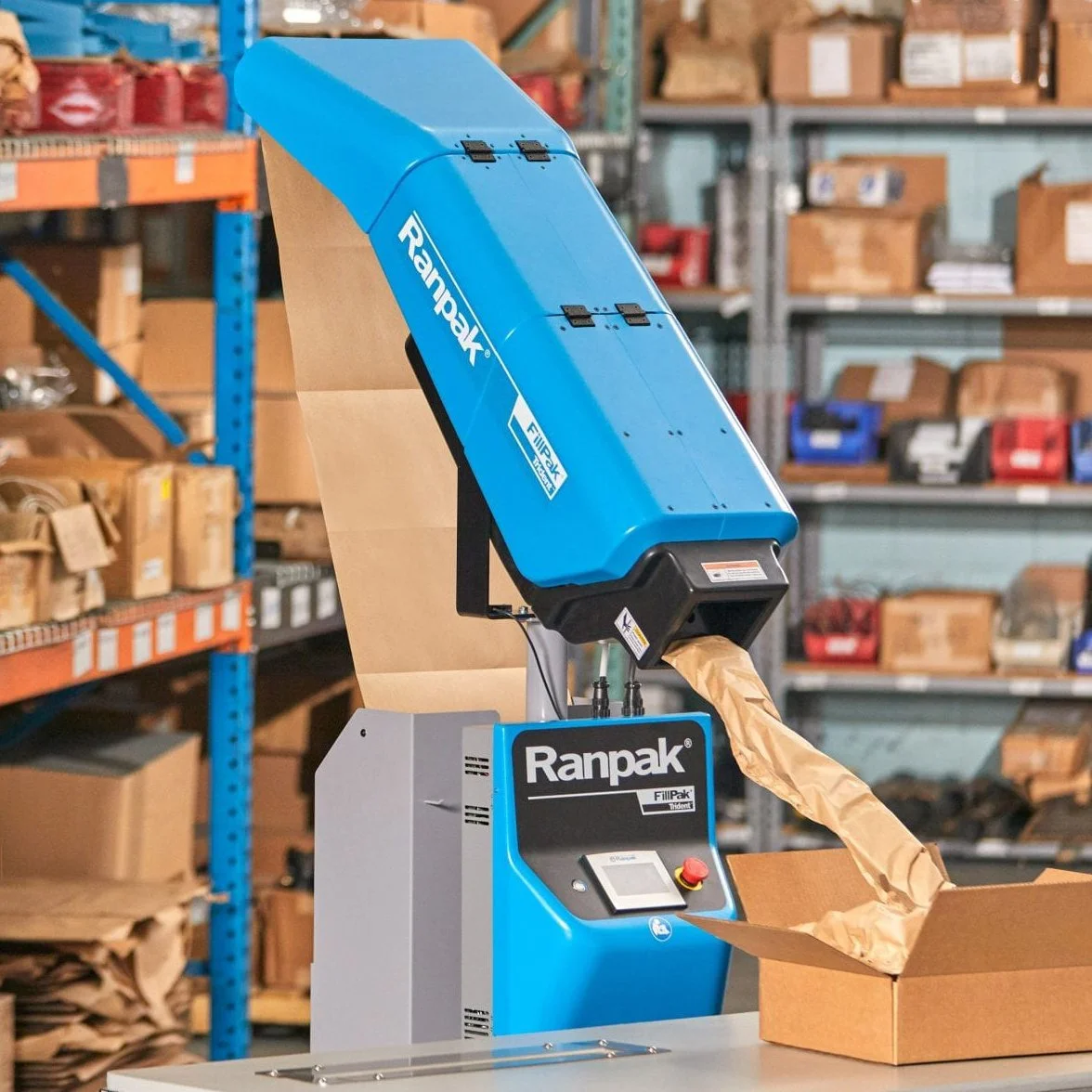 A blue void-fill paper packaging machine in a warehouse