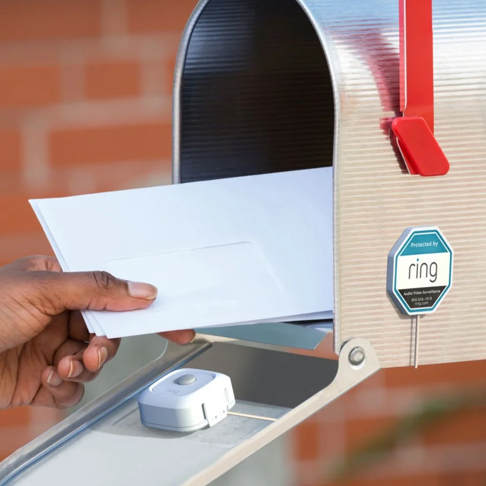 Someone pulling mail out of their mailbox. A Ring mailbox sensor is attached to the outside