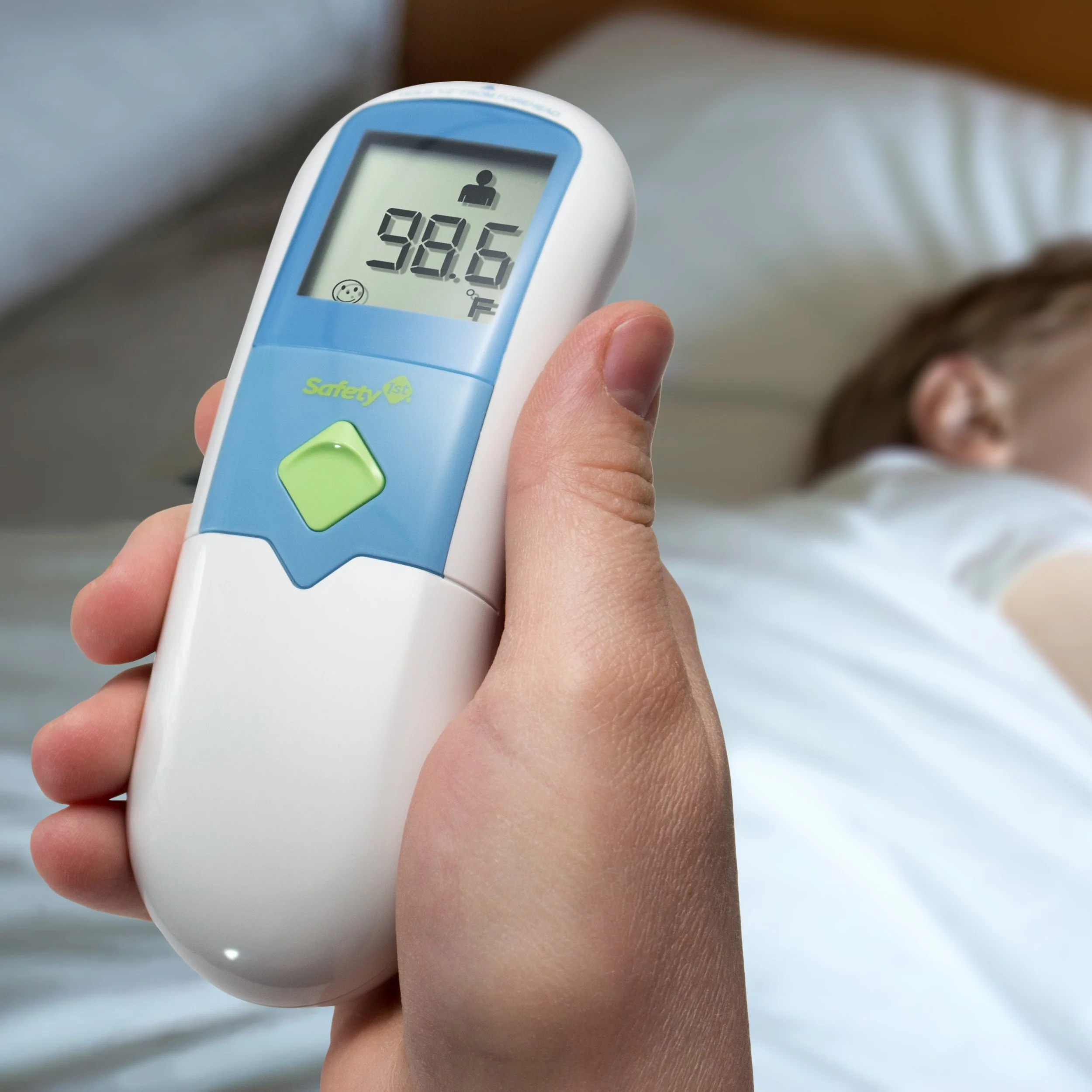 Thermometer in-hand with a sick child in the background