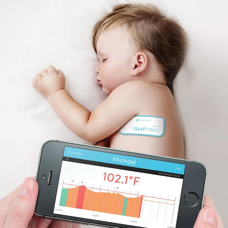 Temperature tracking adhesive patch on a baby with companion app in the foreground
