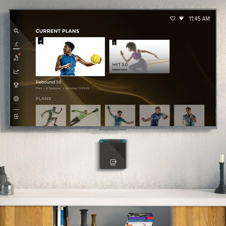 TRAZER device on a wall with a TV displaying the main app dashboard