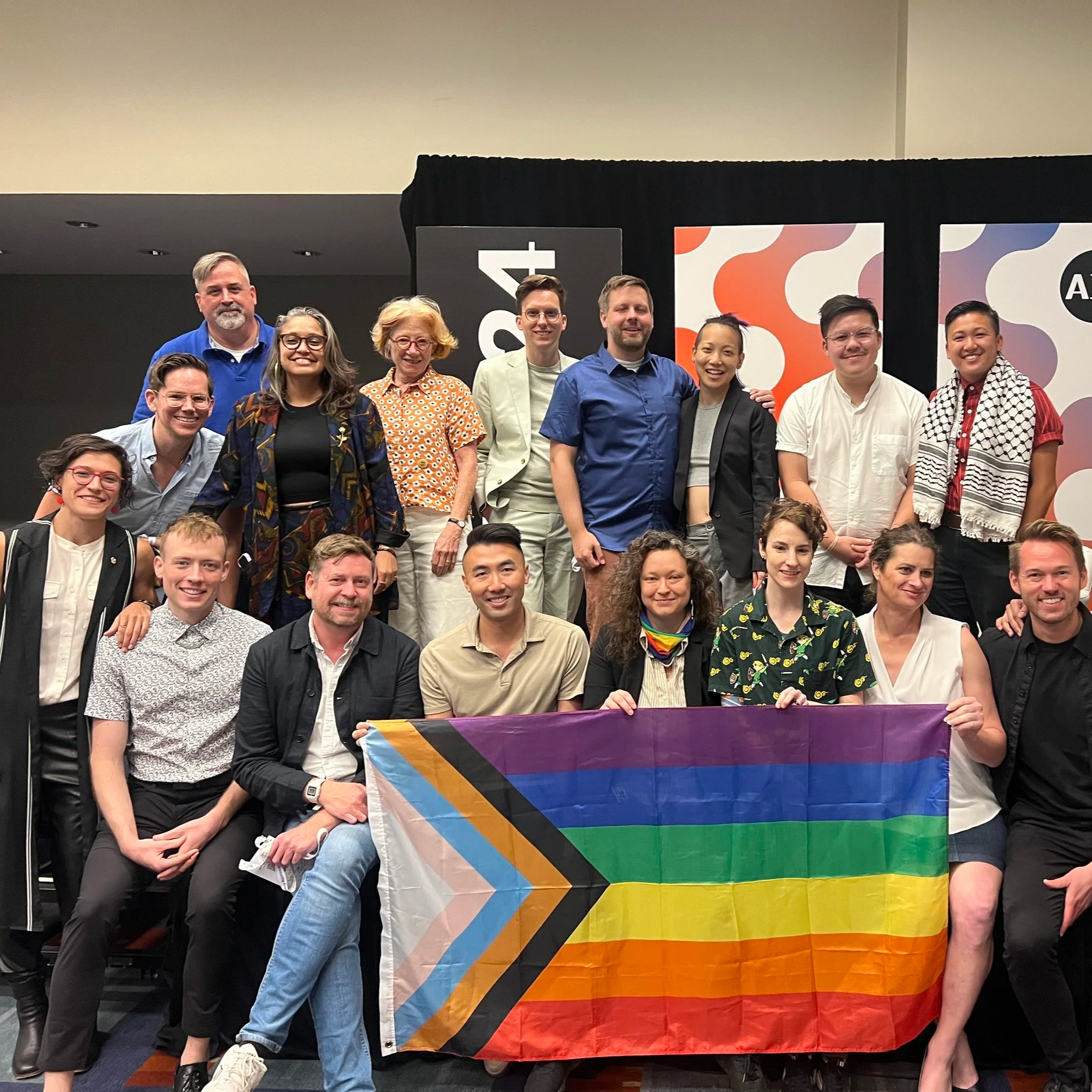 Group of people stands around Pride flag