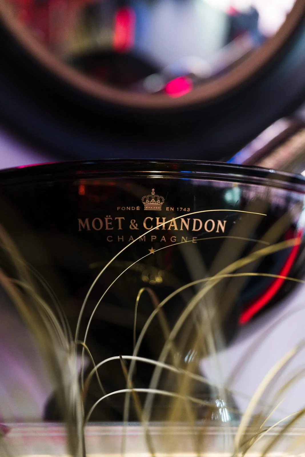 Close-up of a Moët & Chandon champagne bottle in a gift box with gold accents, set against a blurry background.