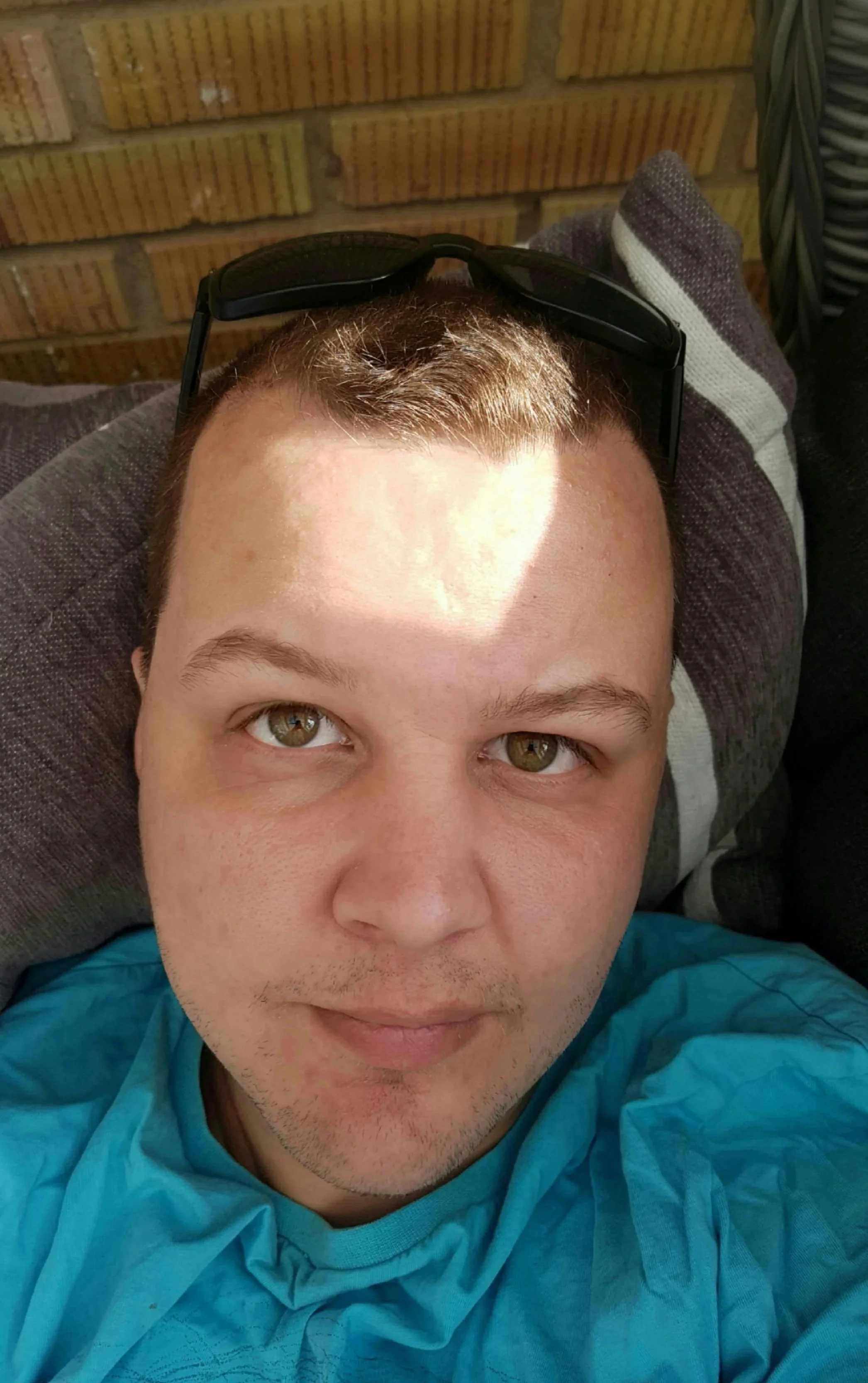 Porträtt av Jimmie Larsson som ligger i en soffa med avslappnat uttryck, ljusbrunt hår och gröna ögon, tittar direkt in i kameran.