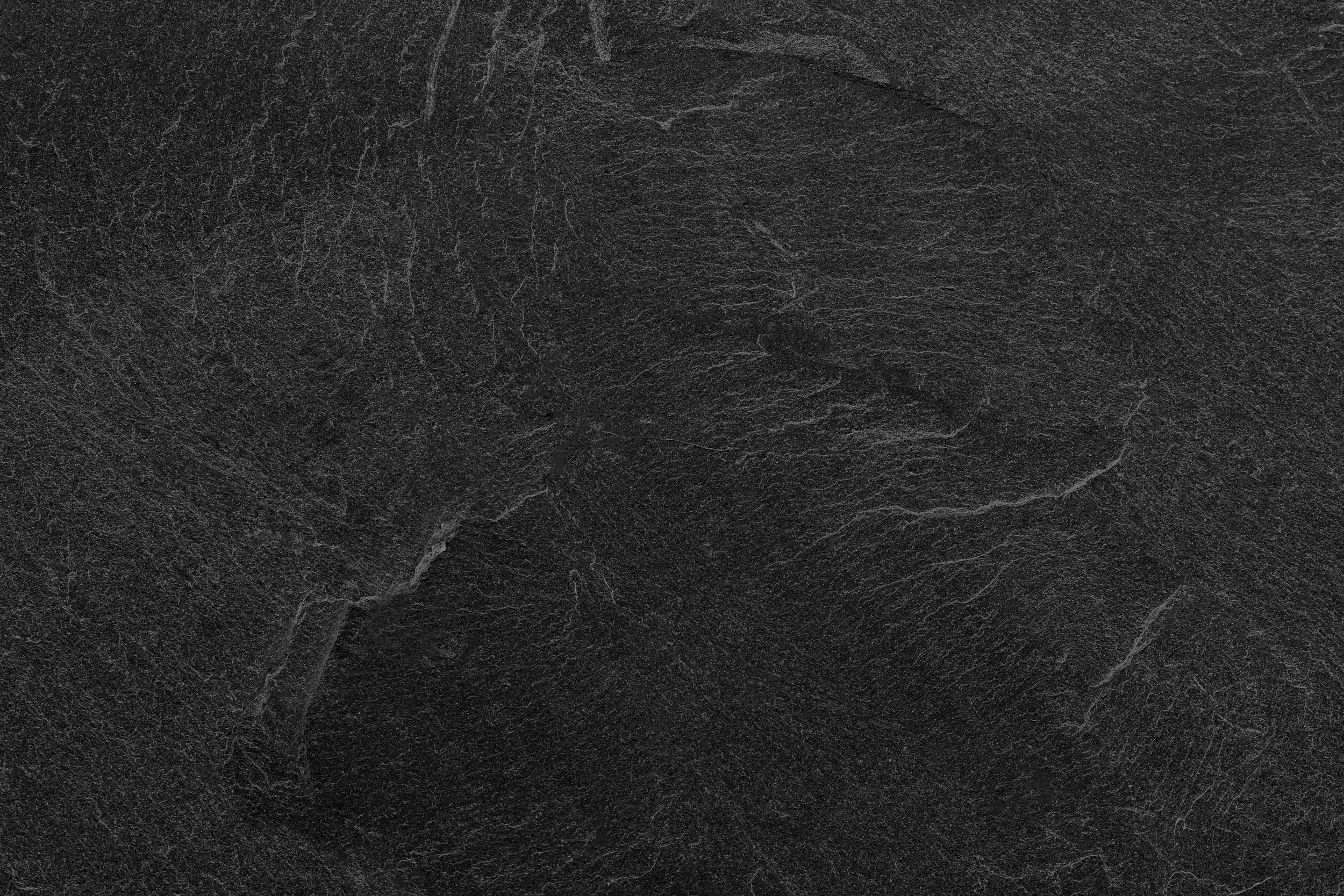Close-up of a textured black slate surface with visible natural grain and white veining.