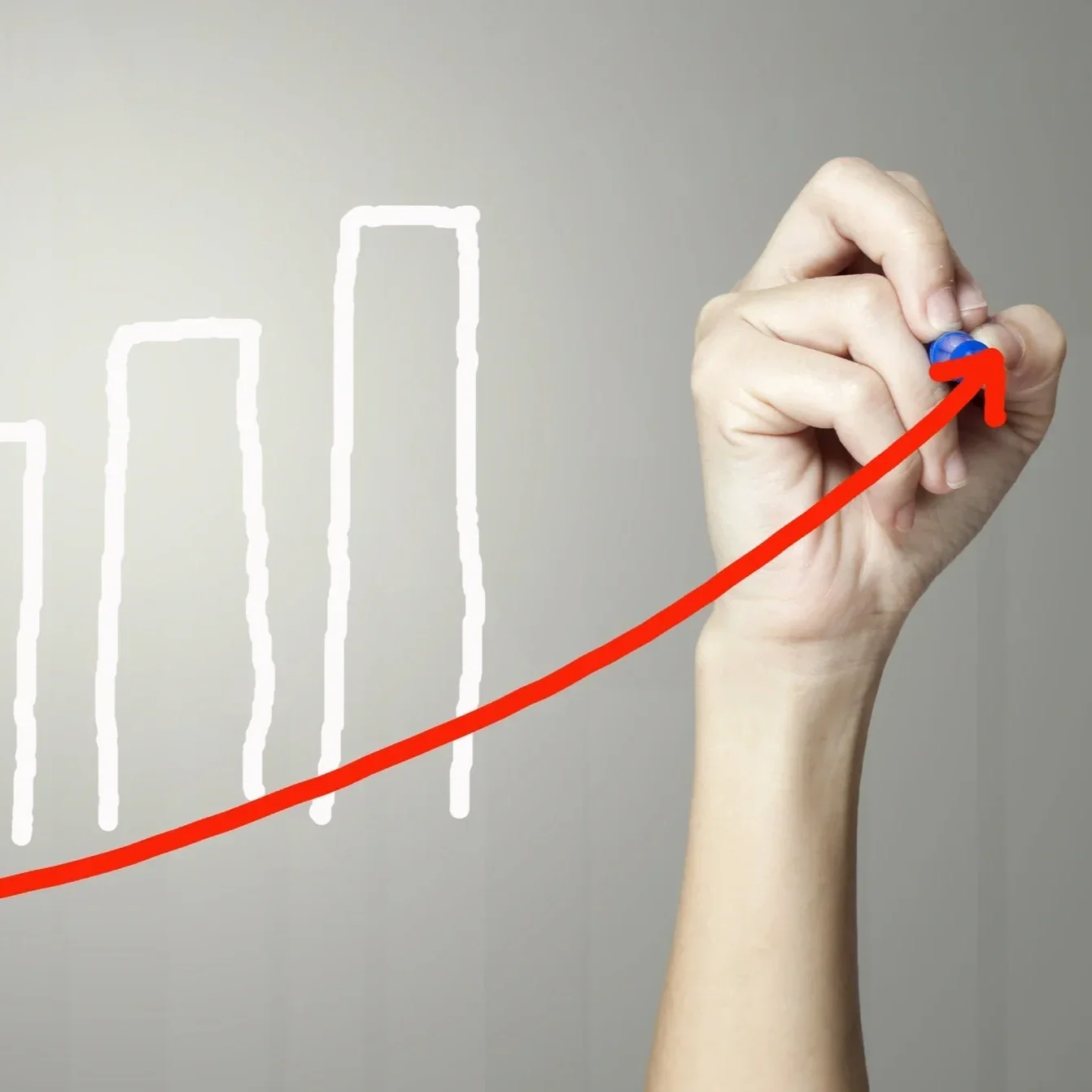 Hand drawing a red upward arrow on a chart with white bars, symbolizing growth and progress.