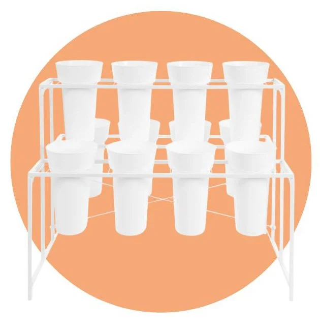 A floral display rack that holds 12 buckets for flower bars containing white buckets on a white metal rack against an orange background.