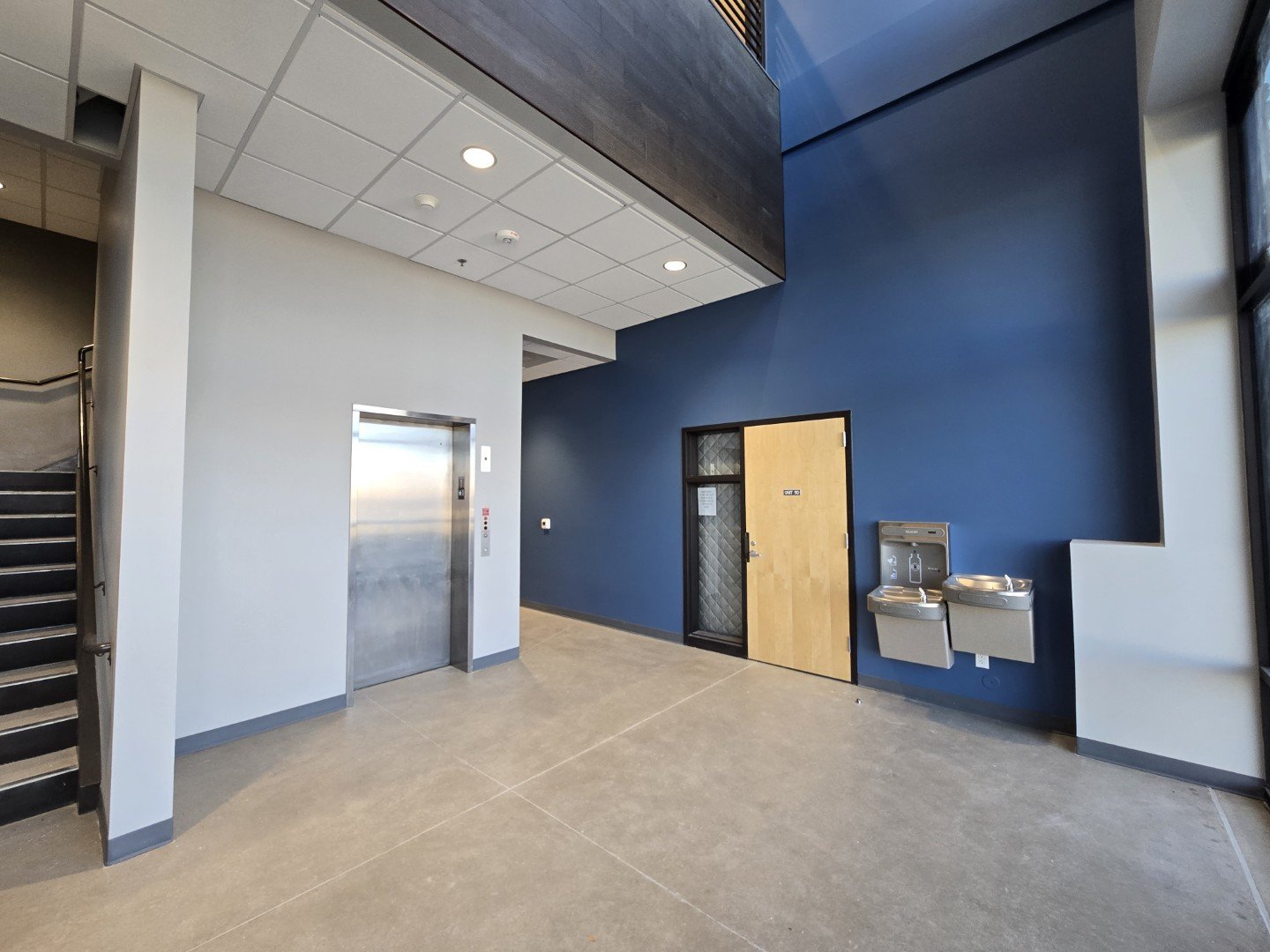 East lobby interior at Own It Vista flex office warehouse condos in Lafayette Colorado showing elevator access, stairwell, and finished lobby area.