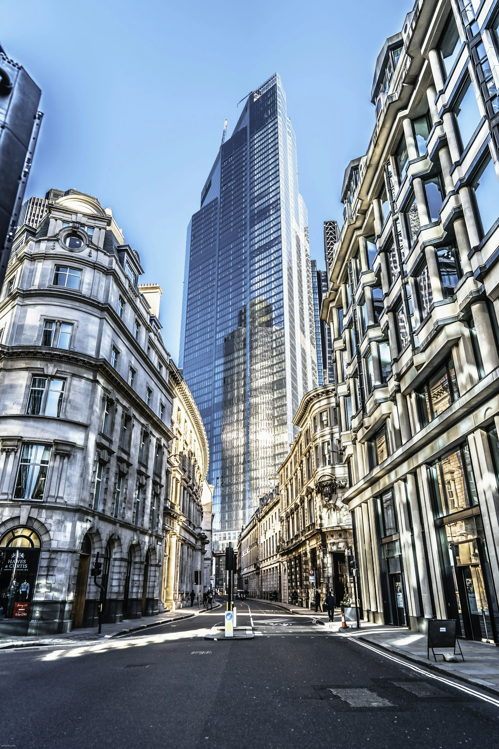 City street surrounded by historic and modern buildings with a clear blue sky overhead.