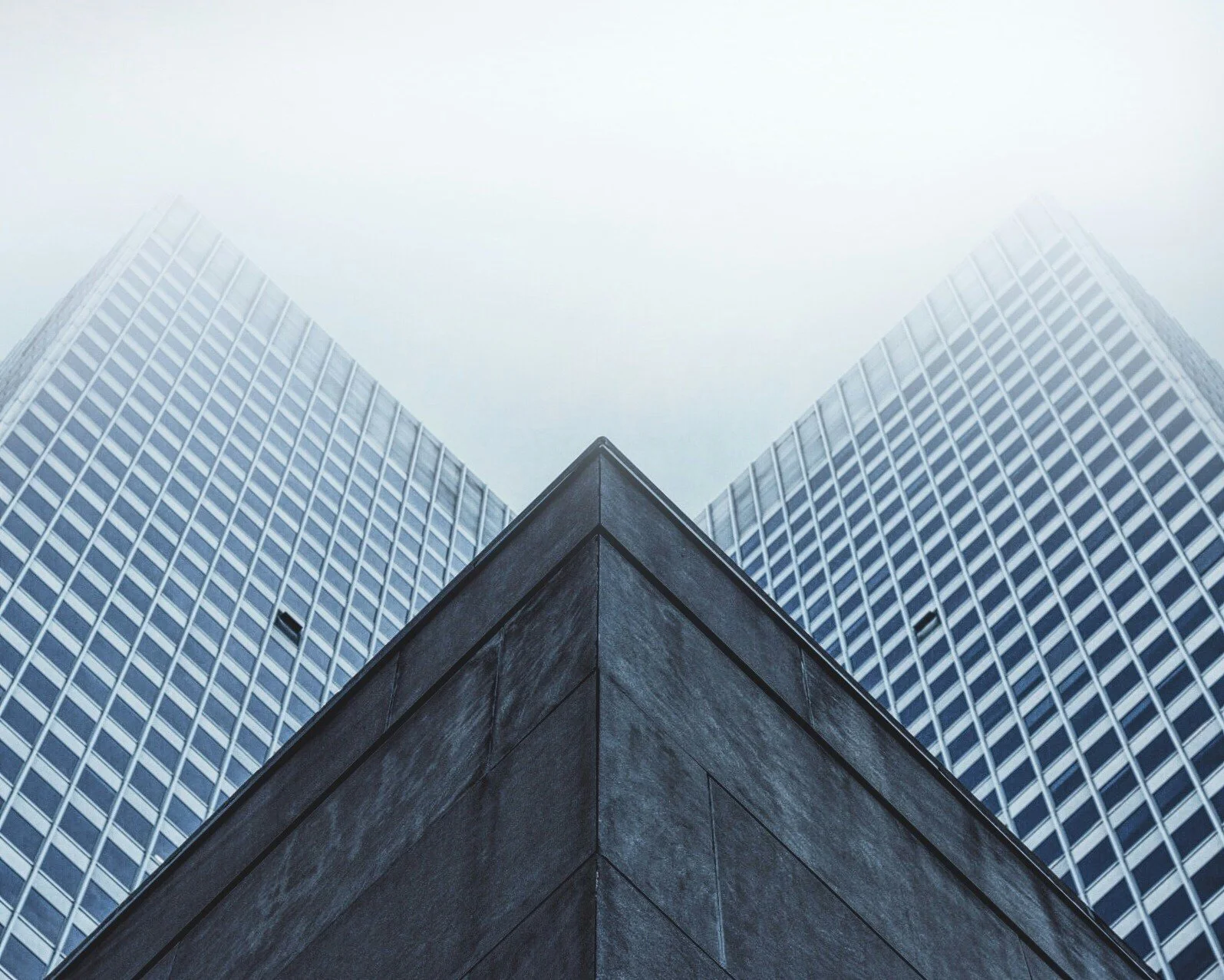 Low angle view of modern glass office buildings with a decorative stone corner wall.