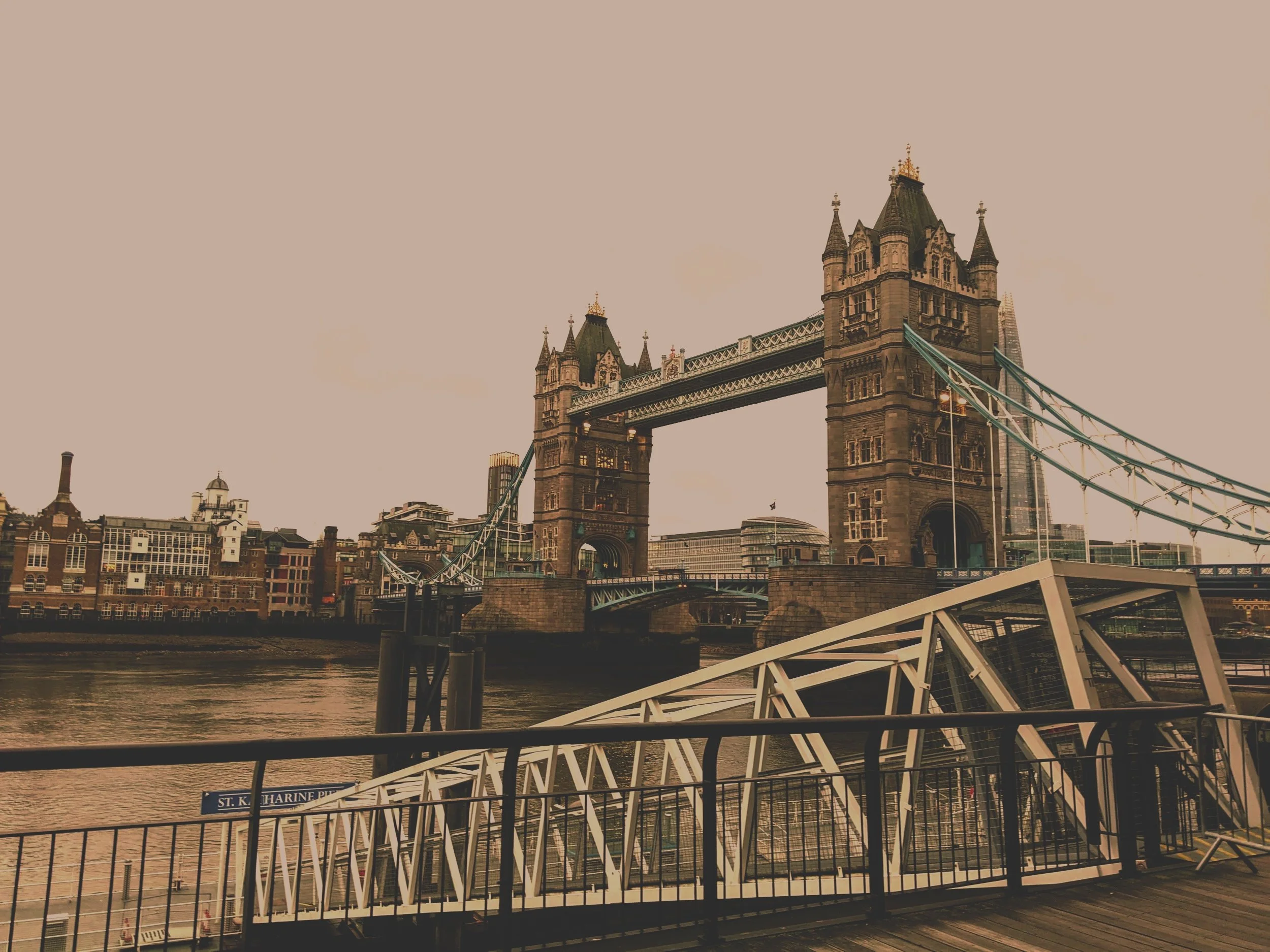 London Tower Bridge over the River Thames with overcast sky and surrounding buildings.