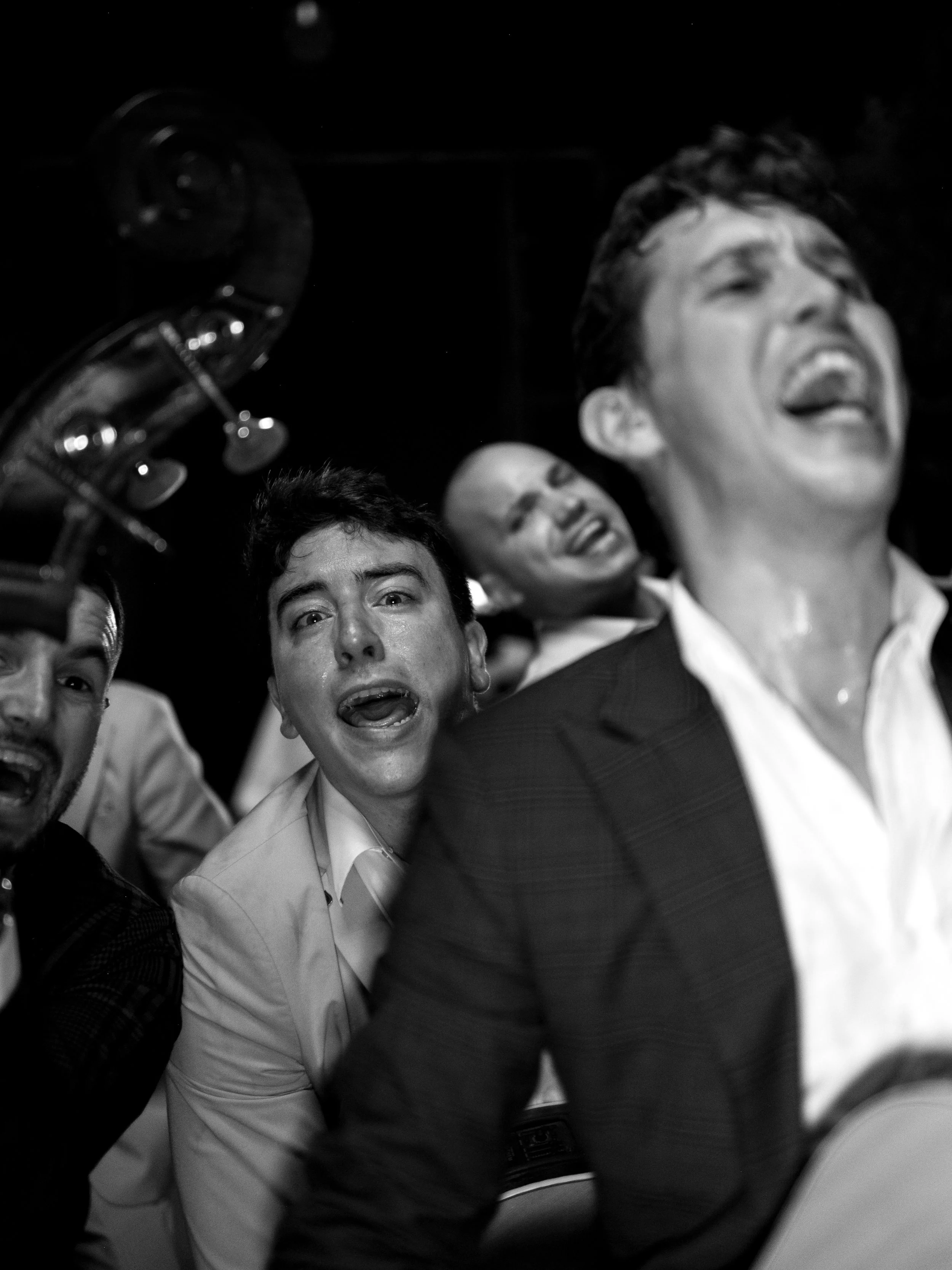 A group of people, including a man playing a guitar, singing or performing in a lively and joyful manner.