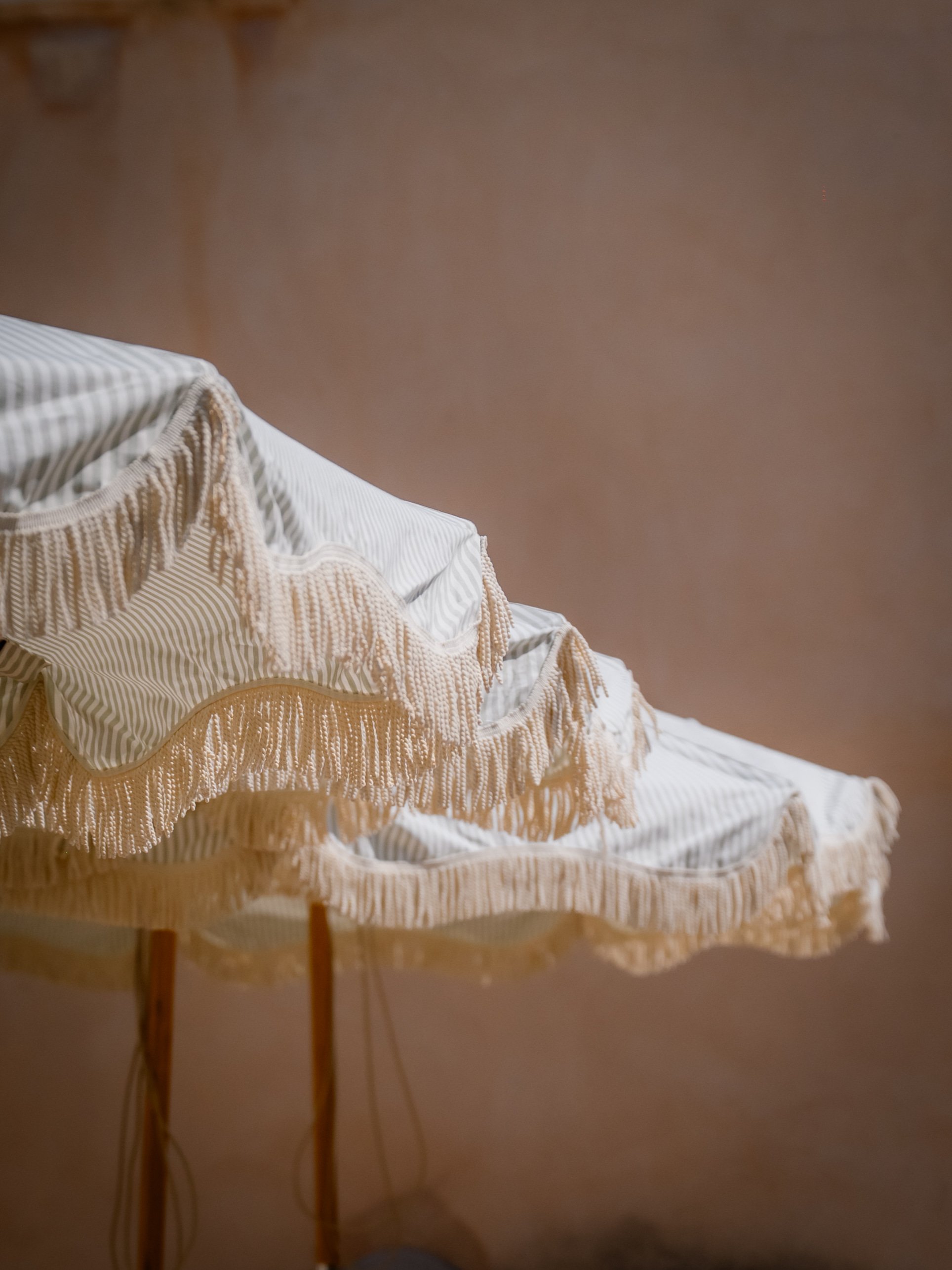 Close-up of a bed with a ruffled, striped, beige and white quilt.