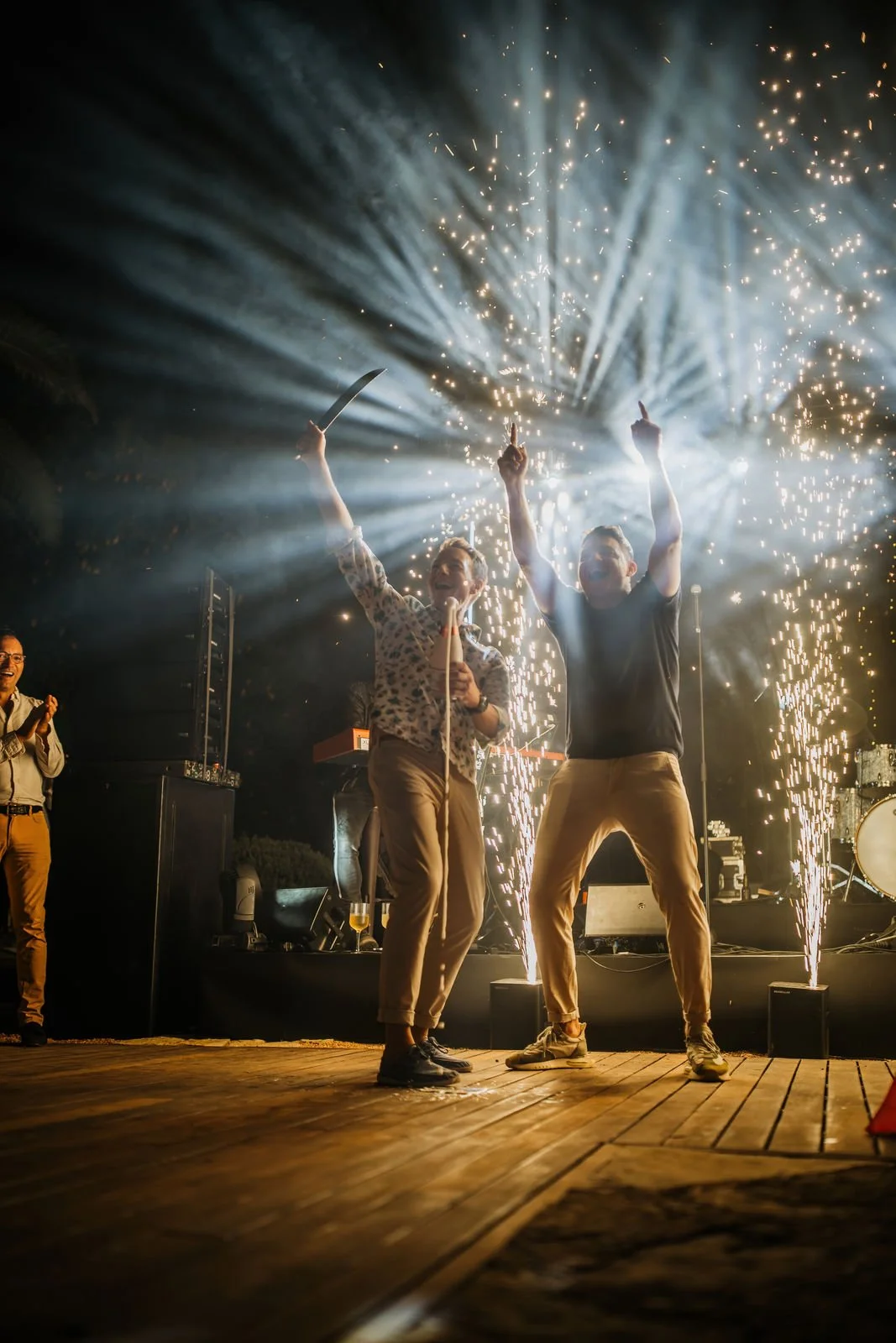People celebrating on stage with fireworks and sparklers.