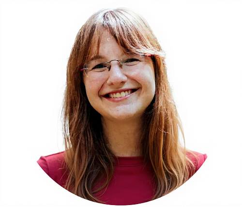 Smiling woman with glasses and long, light brown hair, wearing a maroon top, against a white background.