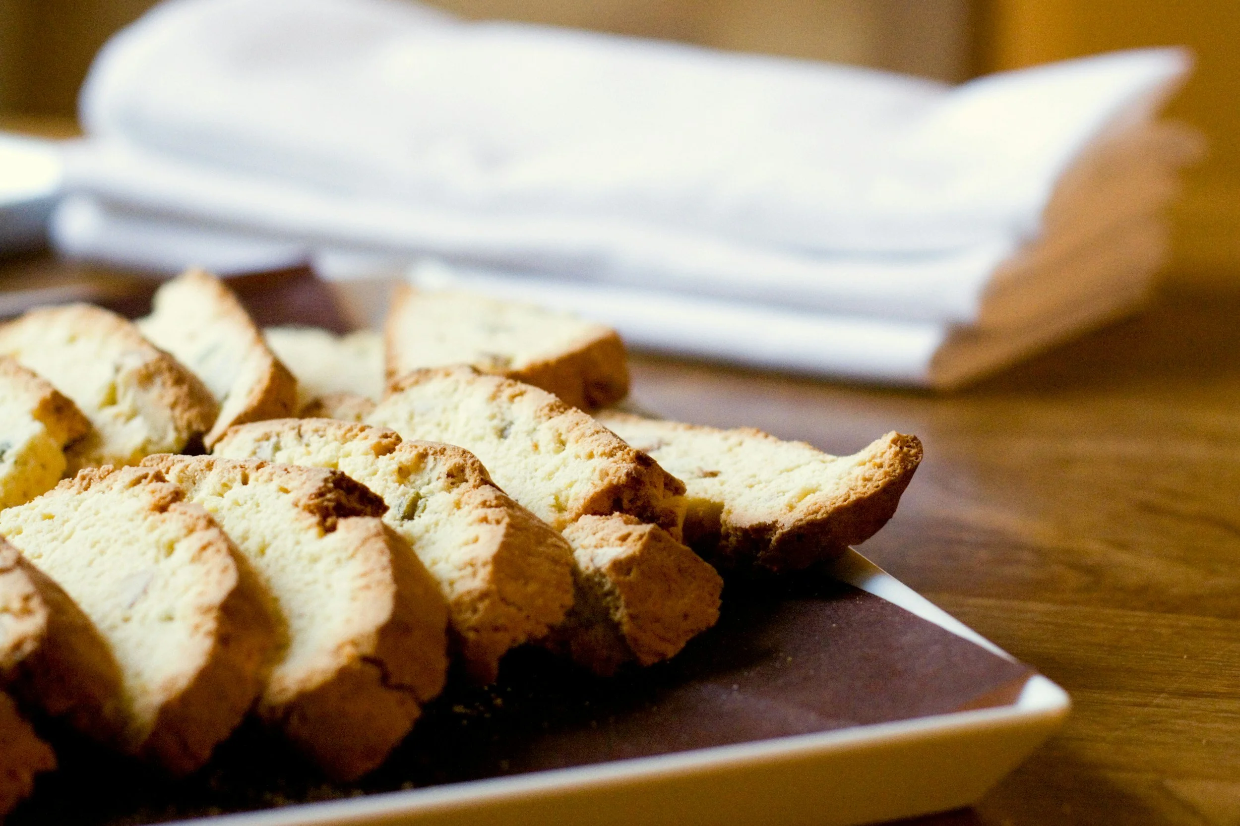 Slices of biscotti on a white rectangular plate with a napkin and knife in the background from The Charcuterie Chics near Asheville NC