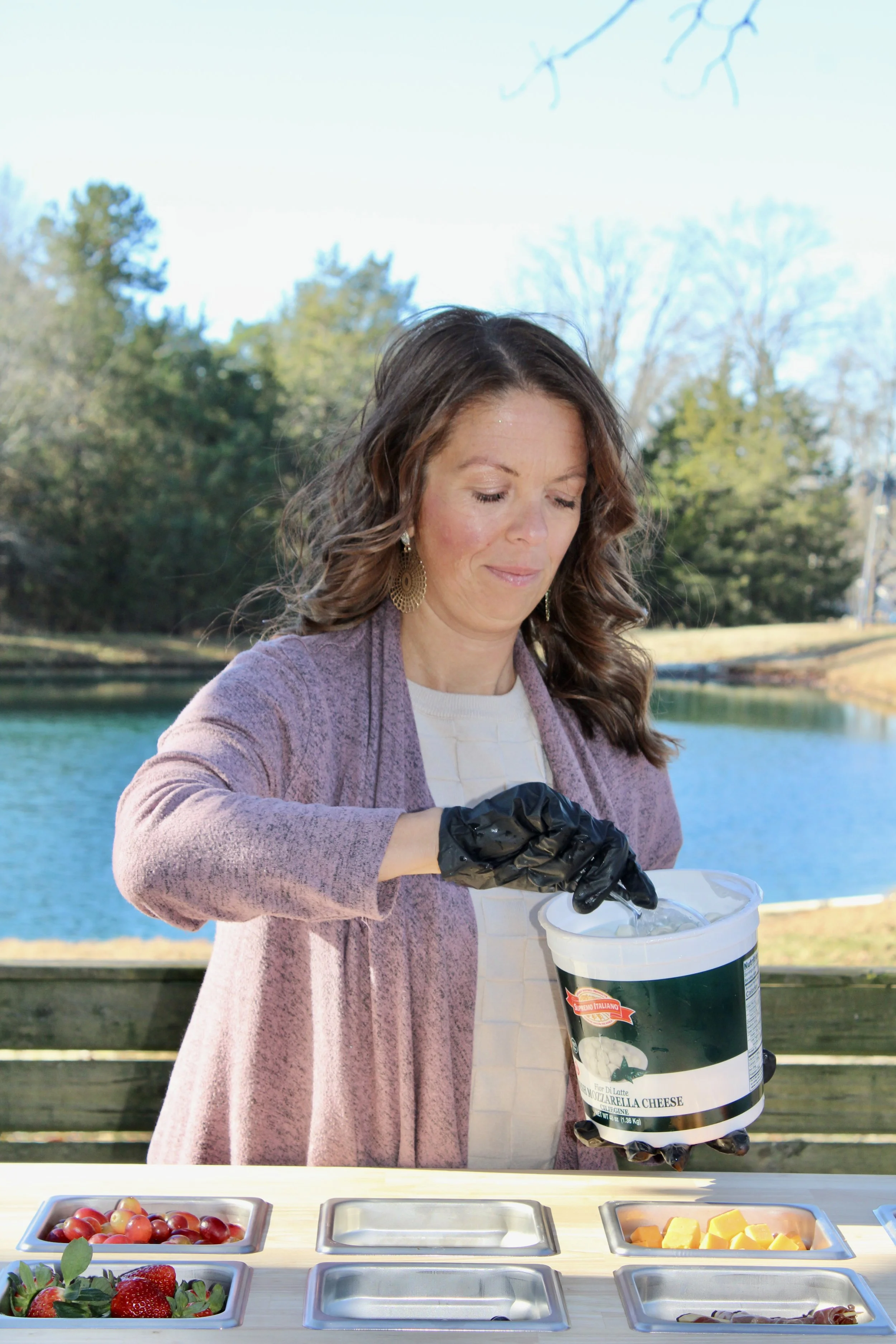 Amber preparing her mobile charcuterie cart with various berries, proteins, and cheeses for an event near Charlotte NC