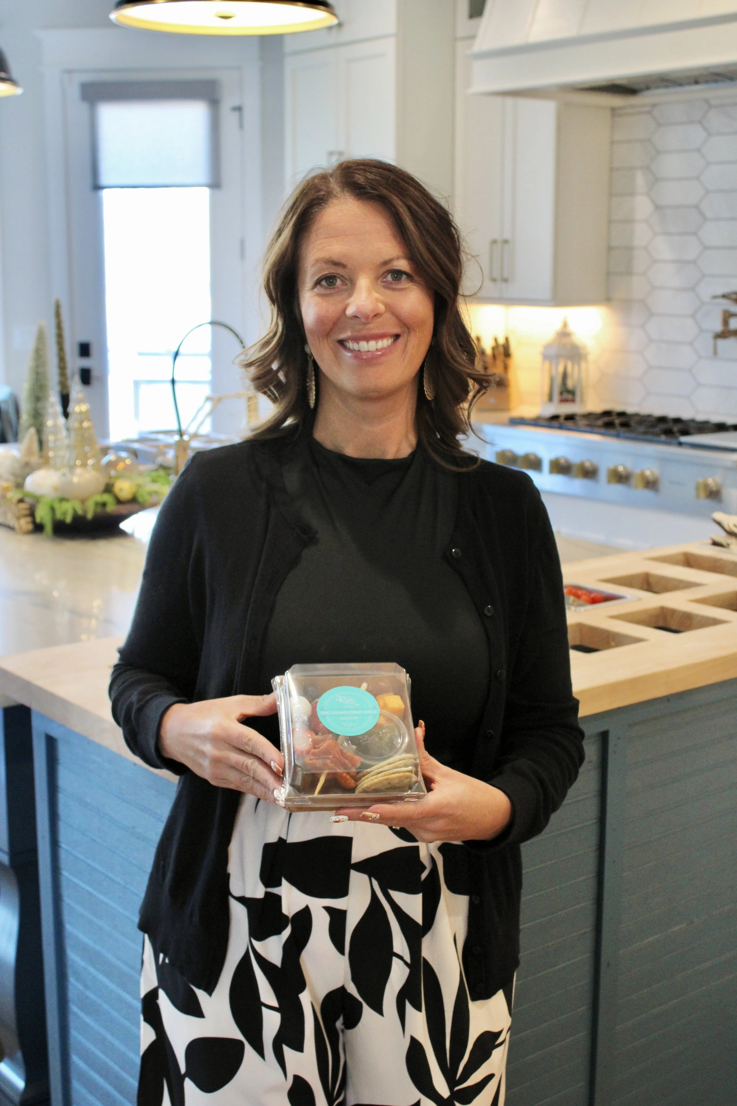 Amber smiling and holding a to-go charcuterie box from The Charcuterie Chics near Boone NC