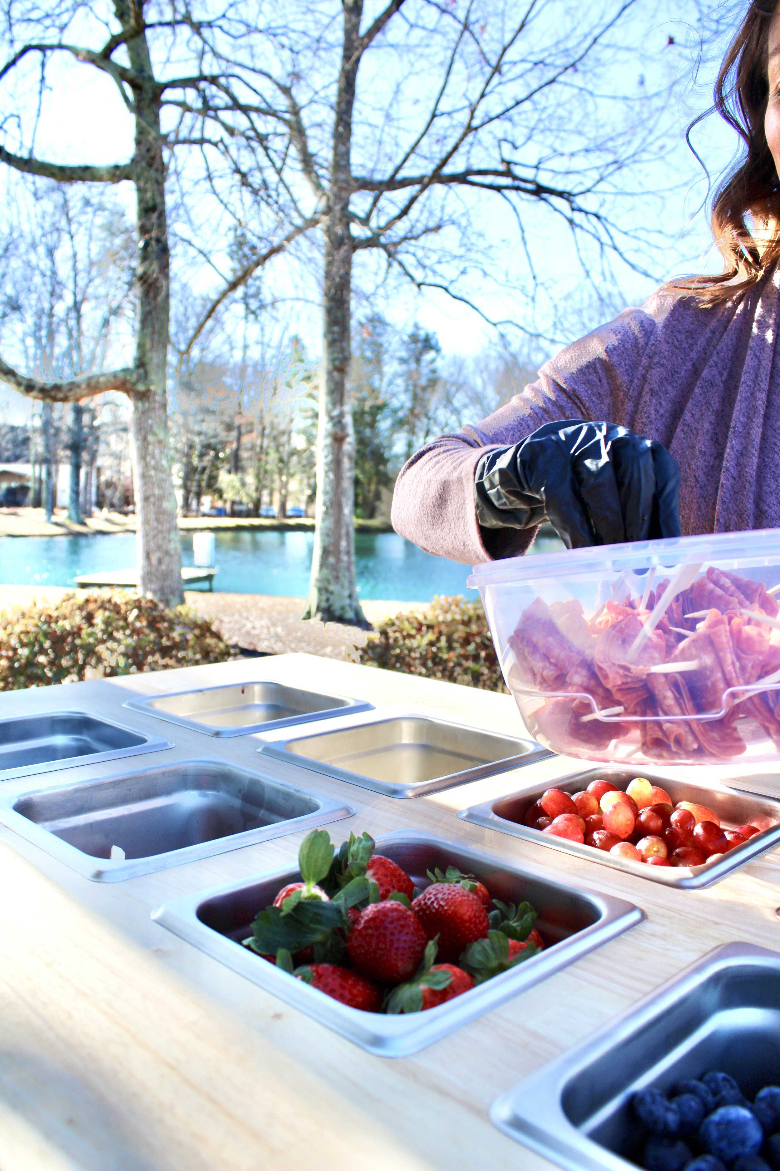 Amber wearing black gloves preparing her mobile charcuterie cart for an event near High Point NC