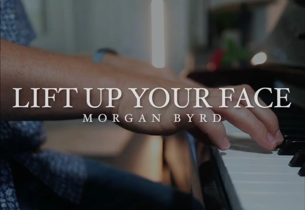 Close-up of a person's hand playing the piano with overlaid text: 'Lift Up Your Face' by Morgan Byrd.
