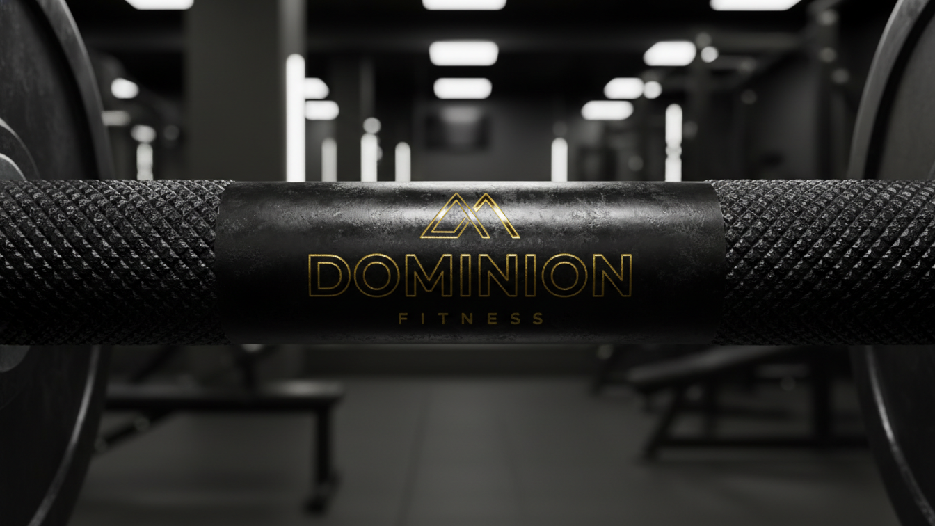 Close-up of a barbell with a label that says 'Dominion Fitness' in a gym.