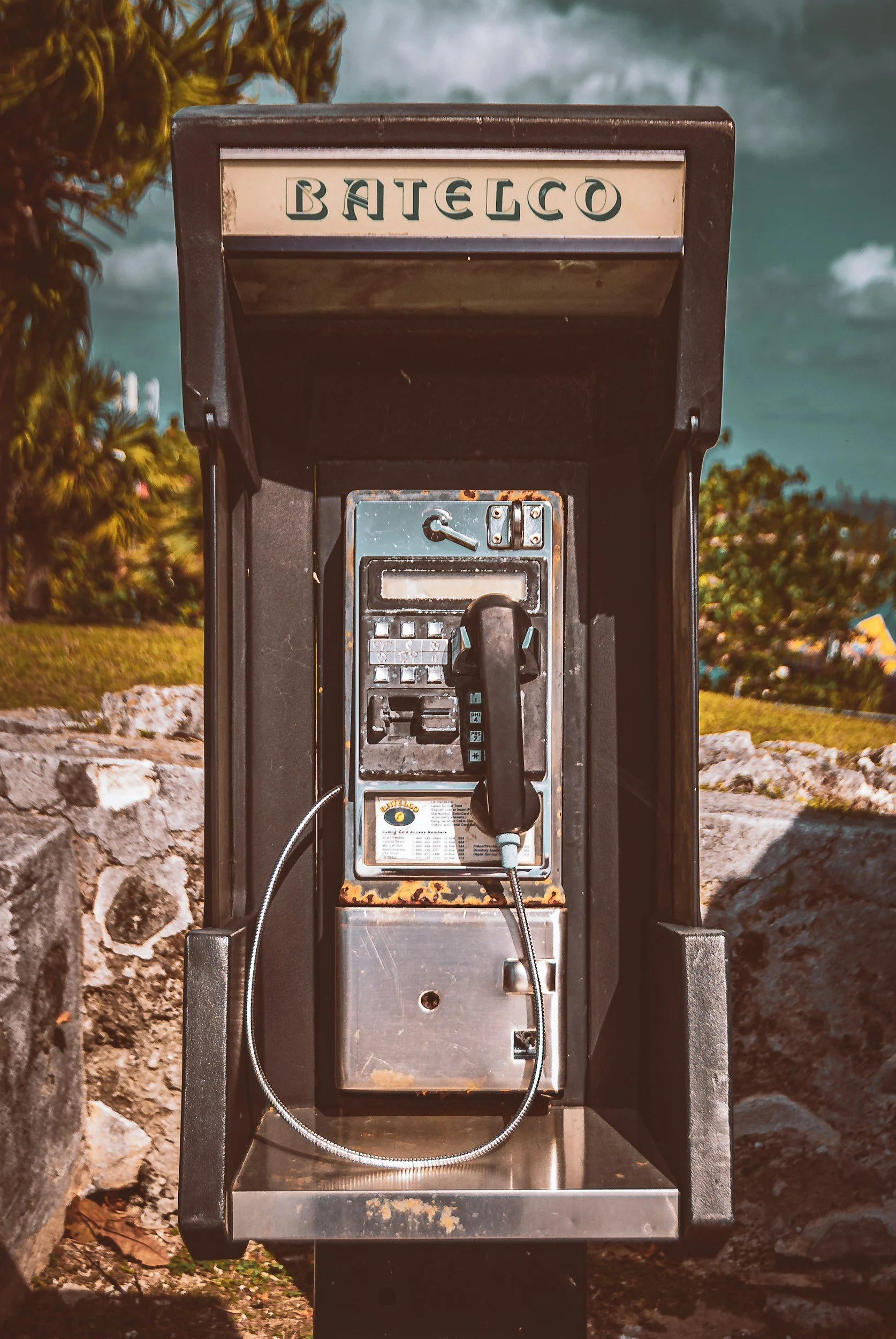 An outside payphone booth with the word 'BATECO' on top, featuring an old-fashioned black telephone.