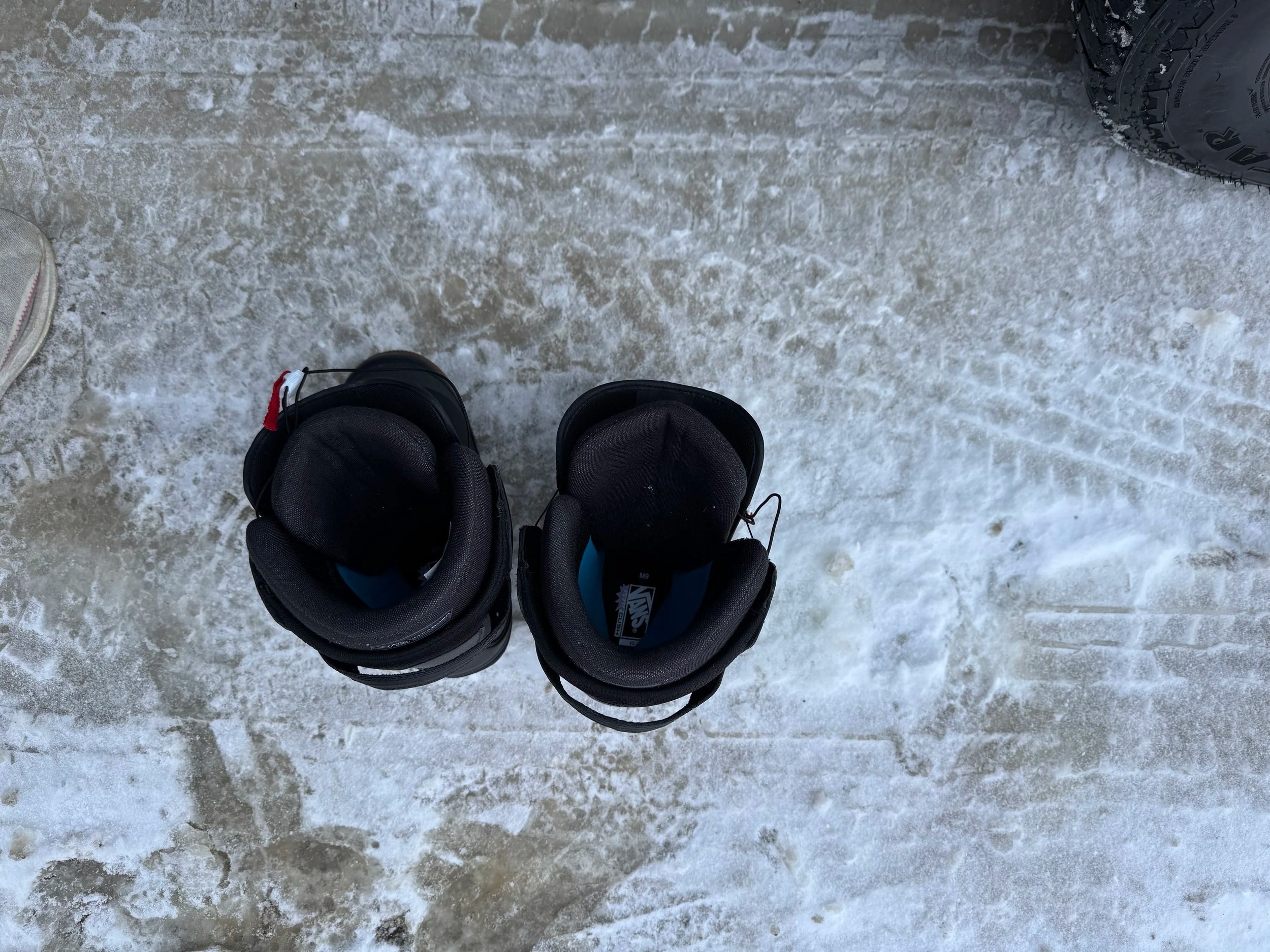 Pair of black snowboard boots on snowy ground.