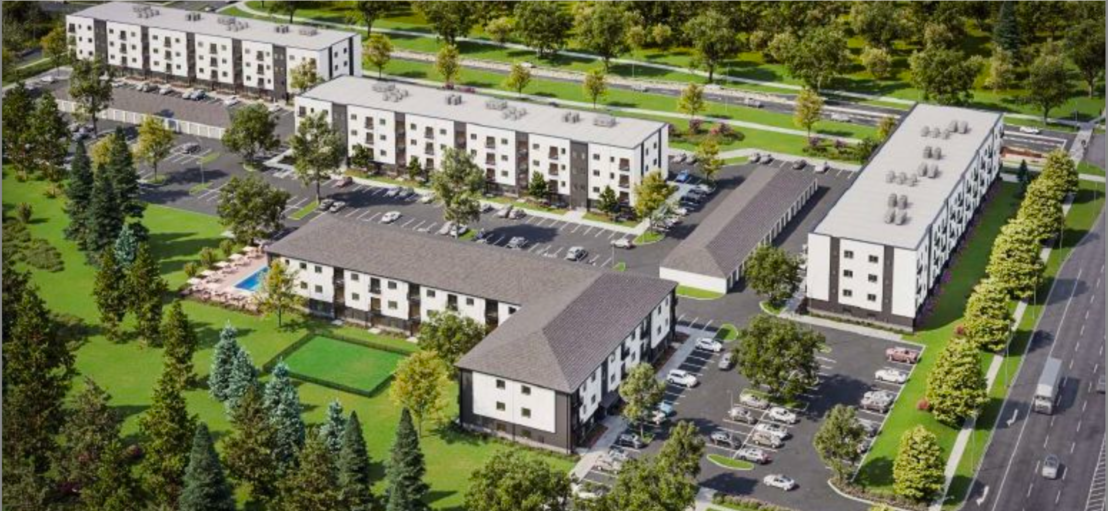 A large residential complex with multiple white and gray apartment buildings surrounded by green trees and landscaped areas. There are parking lots with cars, a swimming pool with lounge chairs, and well-maintained lawns and pathways. The area is bordered by a road with vehicles and trees lining the street.