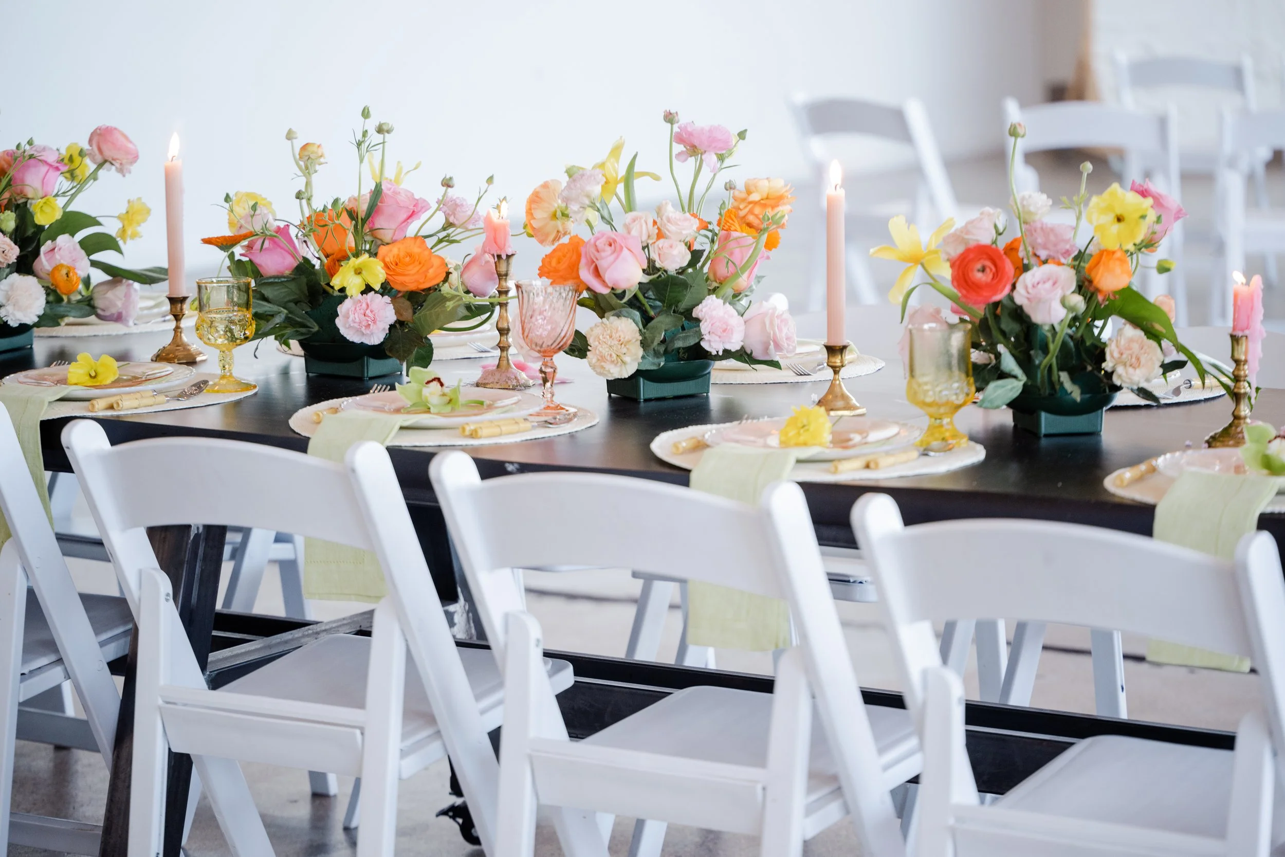 Table decorated with colorful flowers, candles, and elegant glassware for a celebration or event.