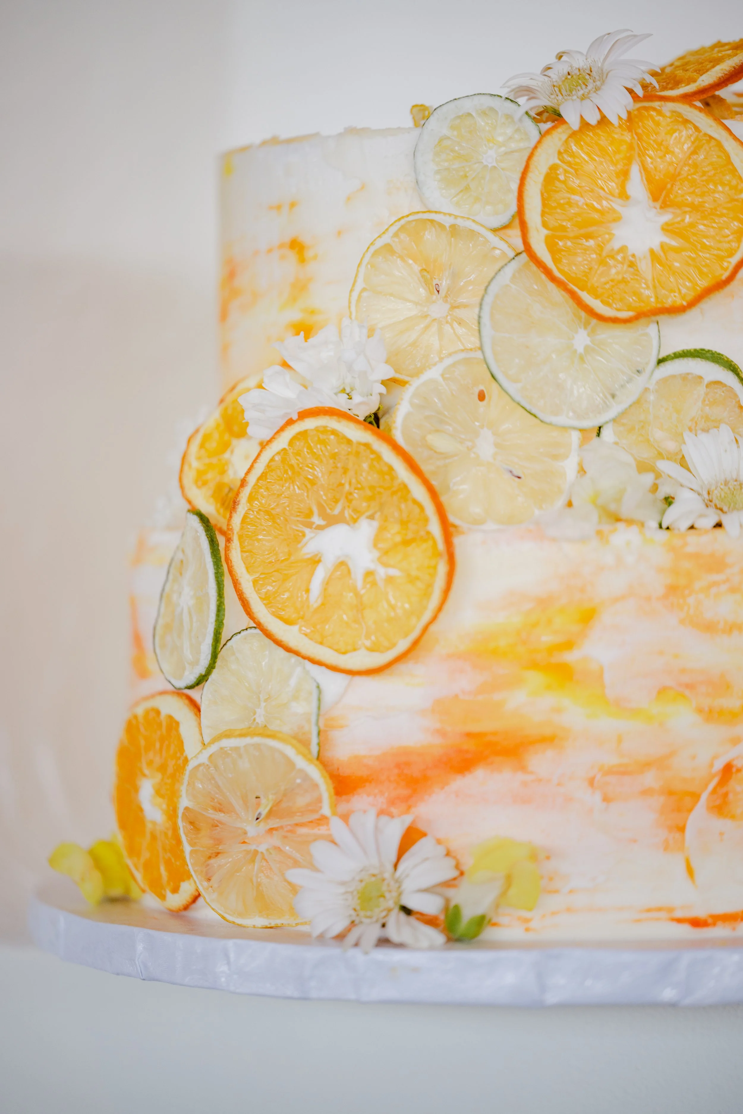 A cake decorated with lemon, lime, and orange slices along with white flowers.